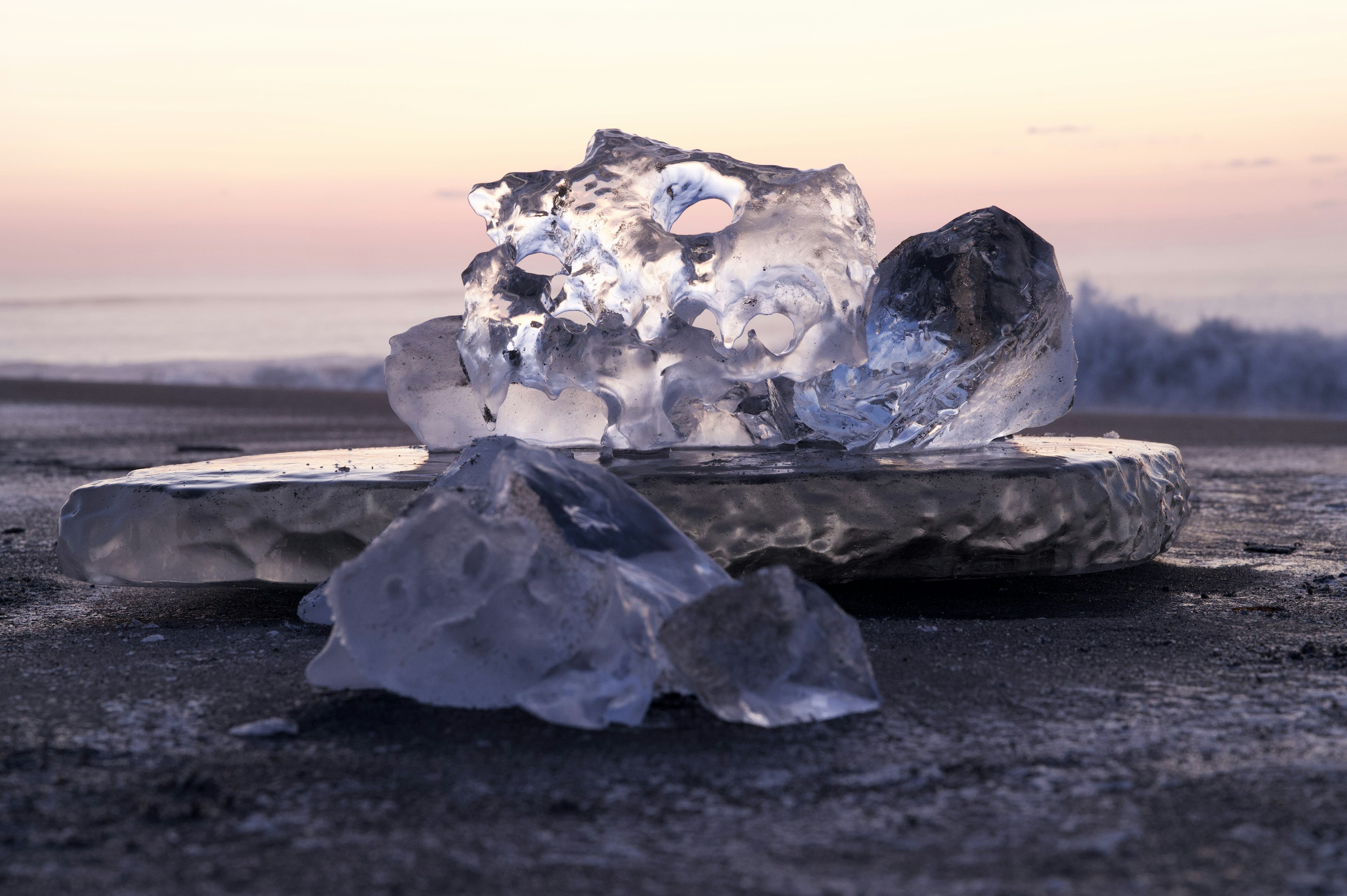 Piezas de hielo sobre una roca con un océano al atardecer