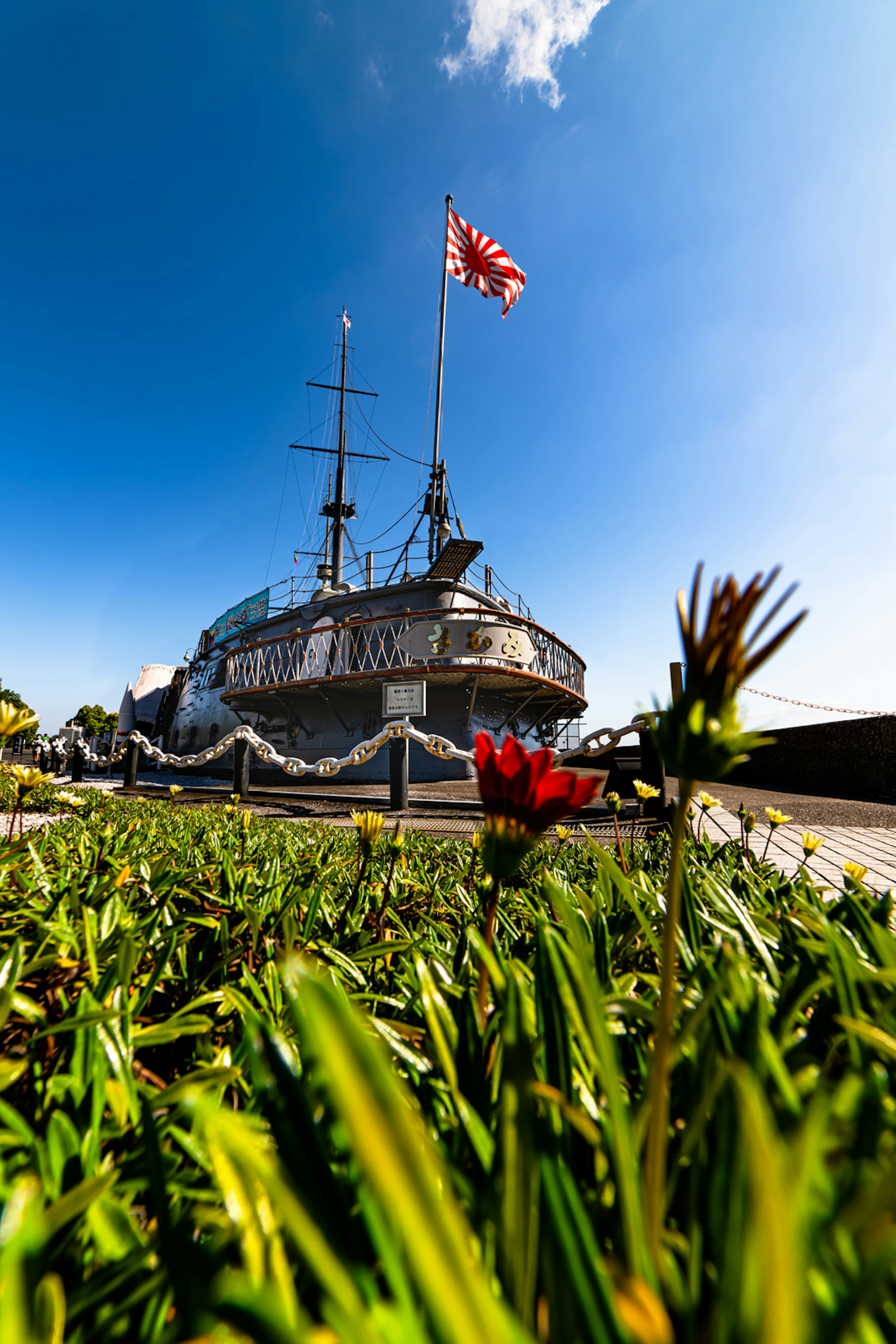 Close-up of a ship under a blue sky with flowers in the foreground