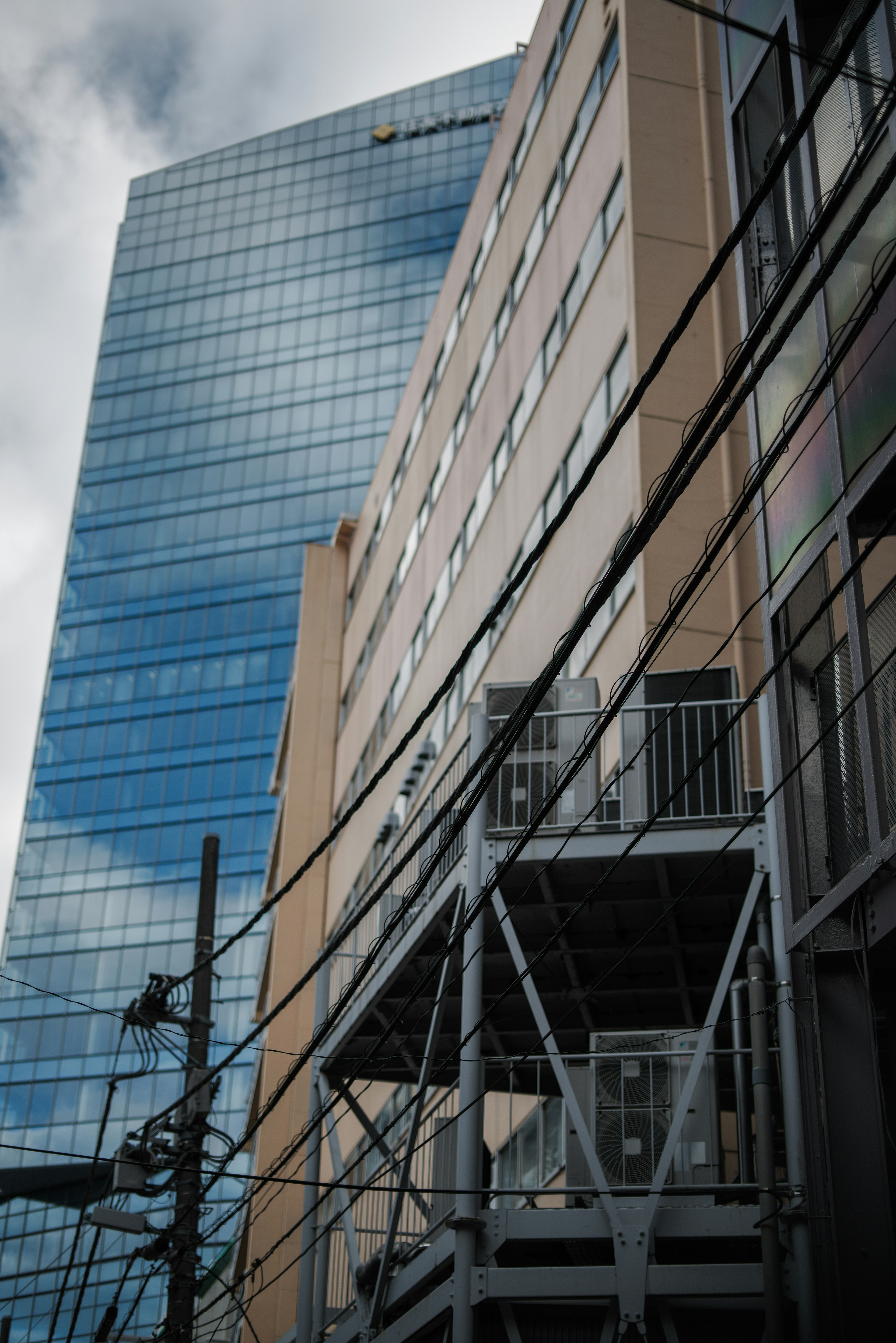 Urban scene showcasing a contrast between a high-rise building and a low-rise structure with intersecting power lines