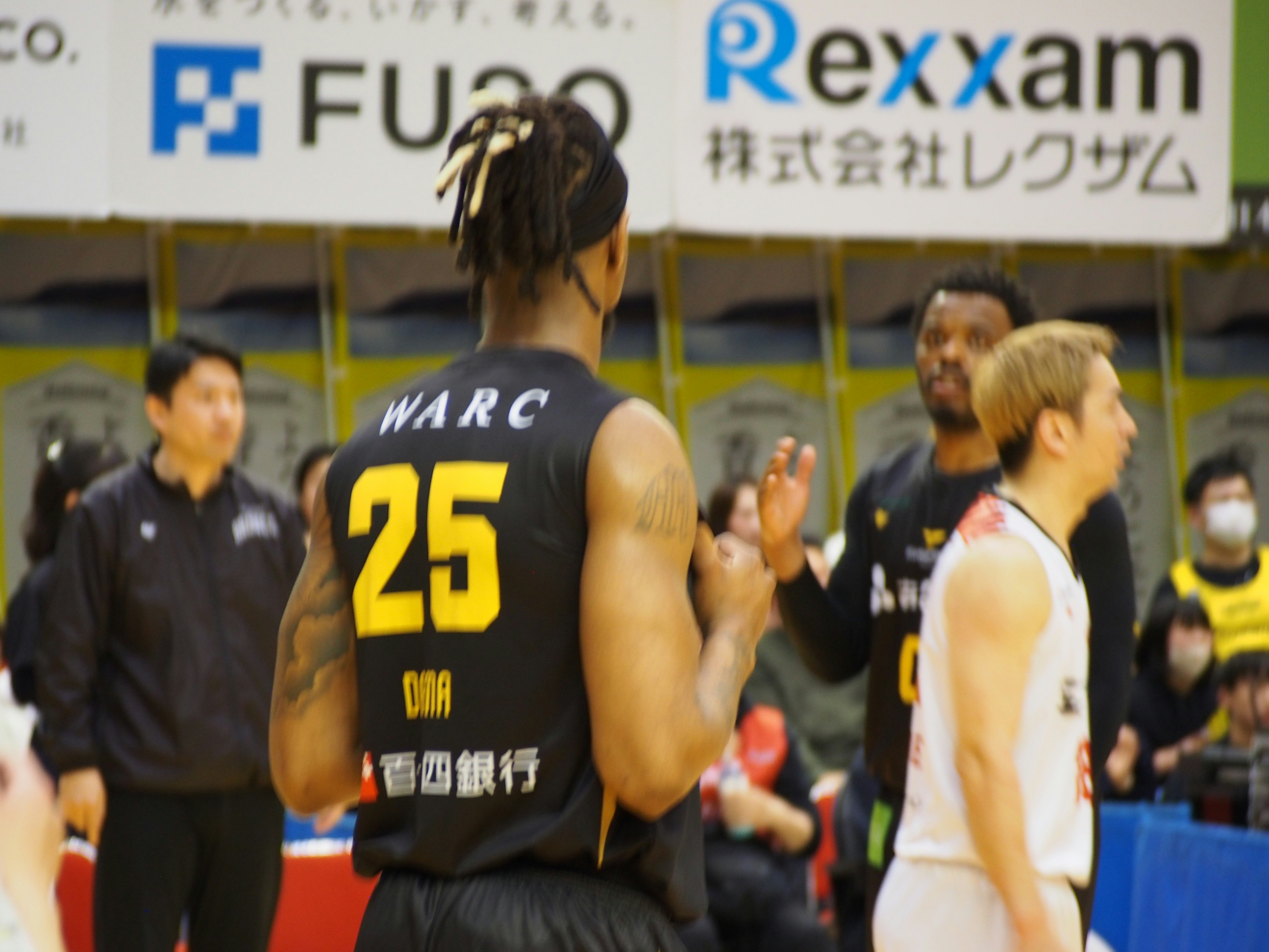 Scène de joueurs de basket-ball interagissant pendant un match avec le joueur numéro 25 en maillot WARC