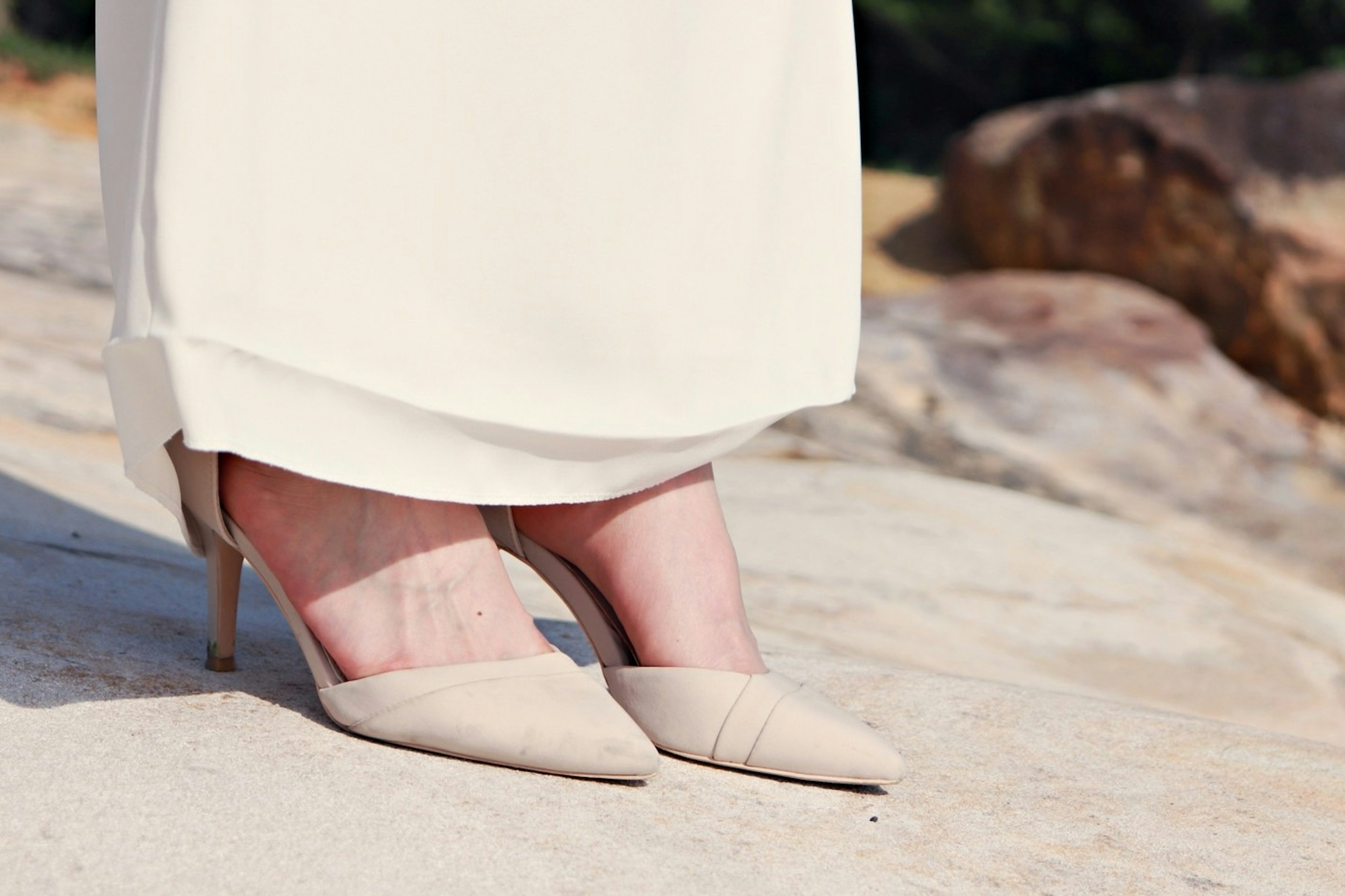 Beige high heels visible beneath a white dress