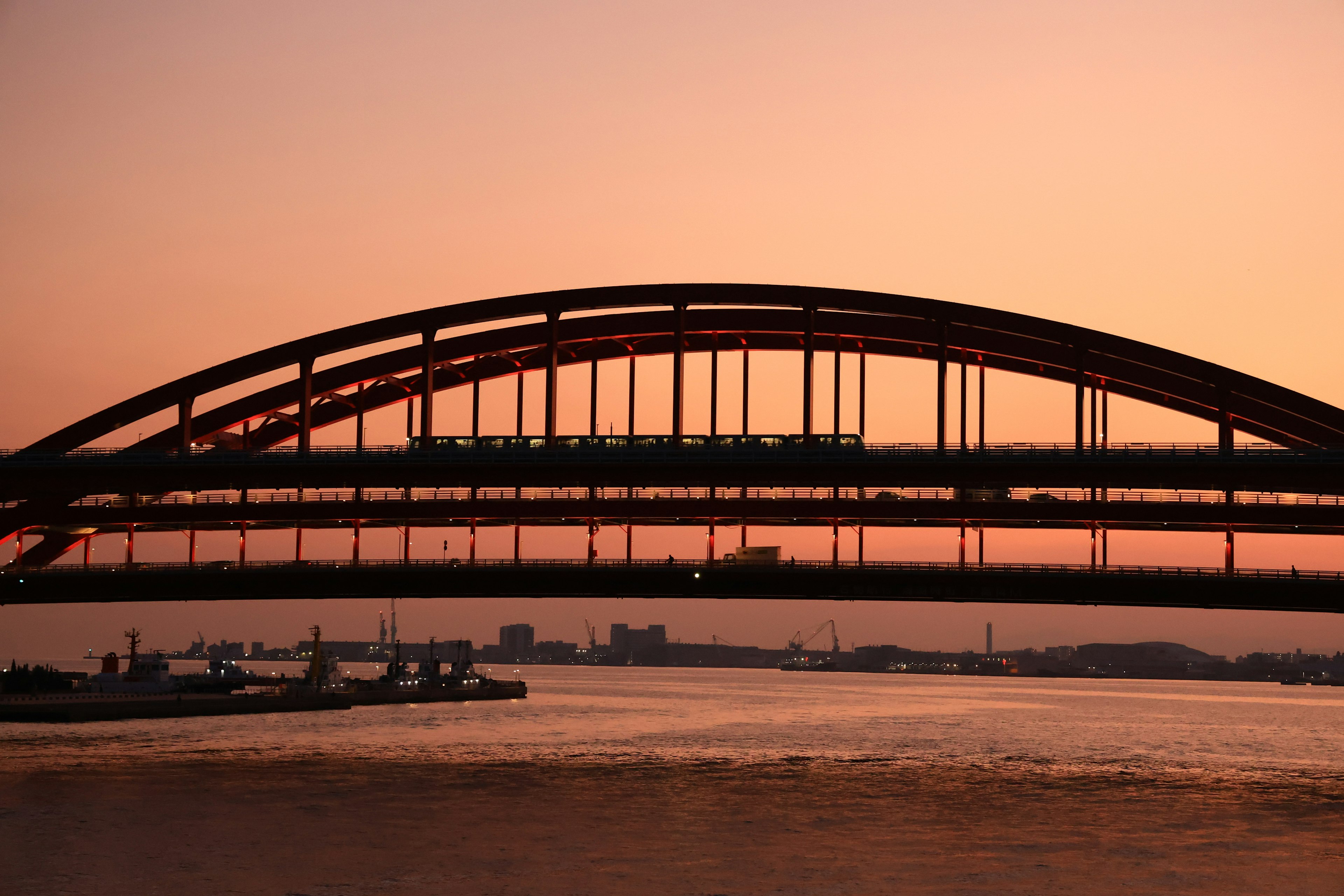 Arch bridge silhouetted against a sunset sky with calm water