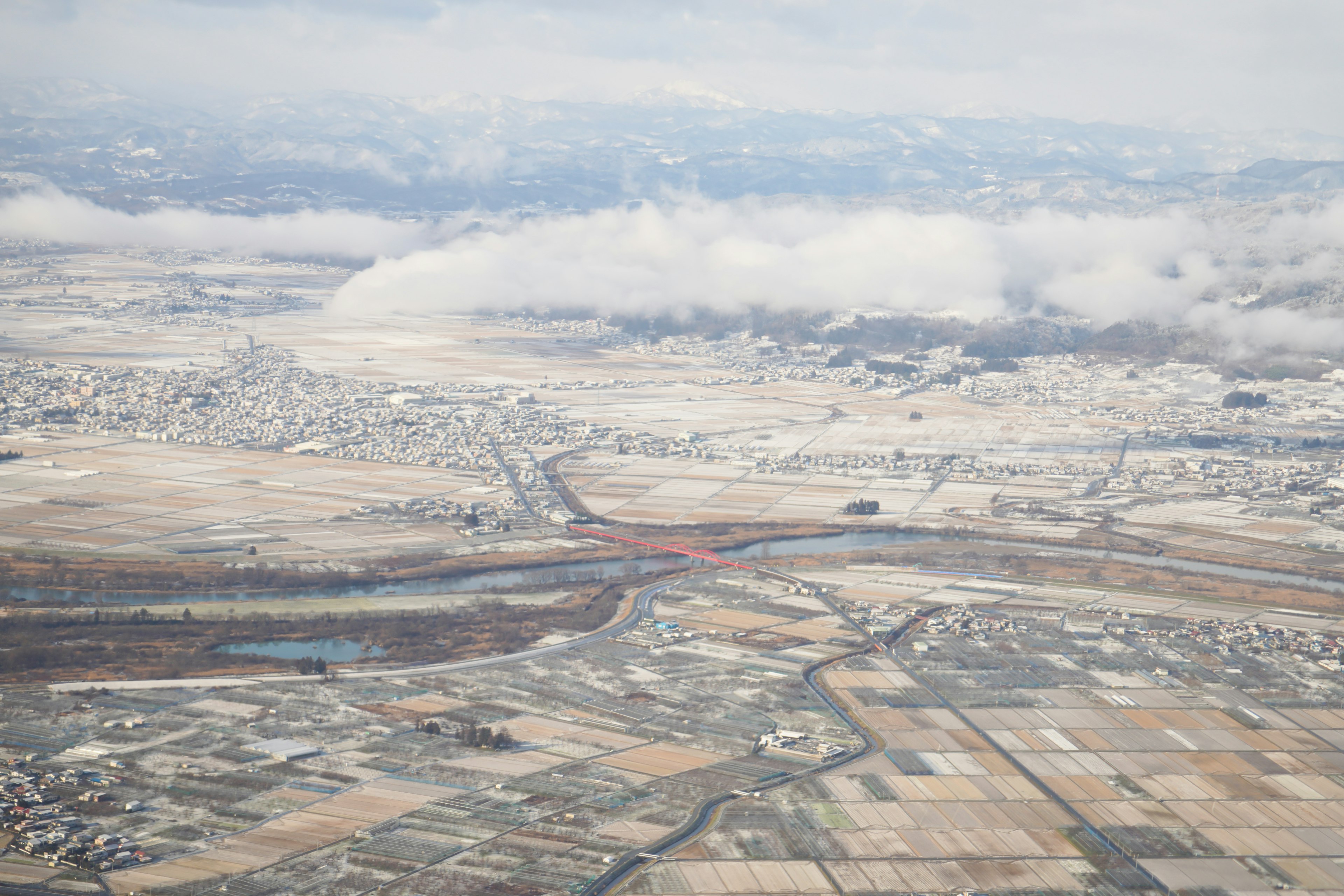 Aerial view of snow-covered landscape with a river flowing through farmland