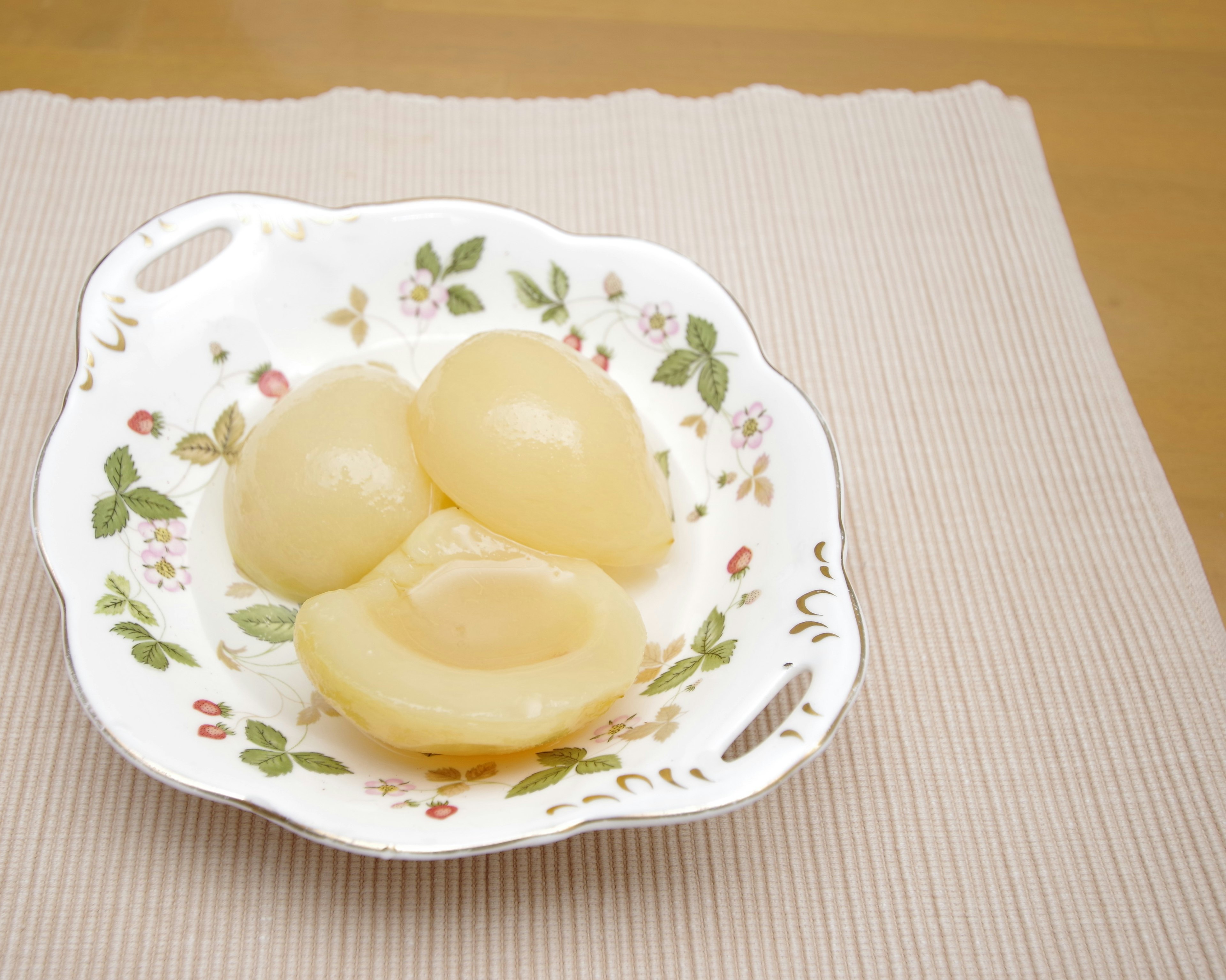 Sweet canned yellow peaches served on a white floral plate