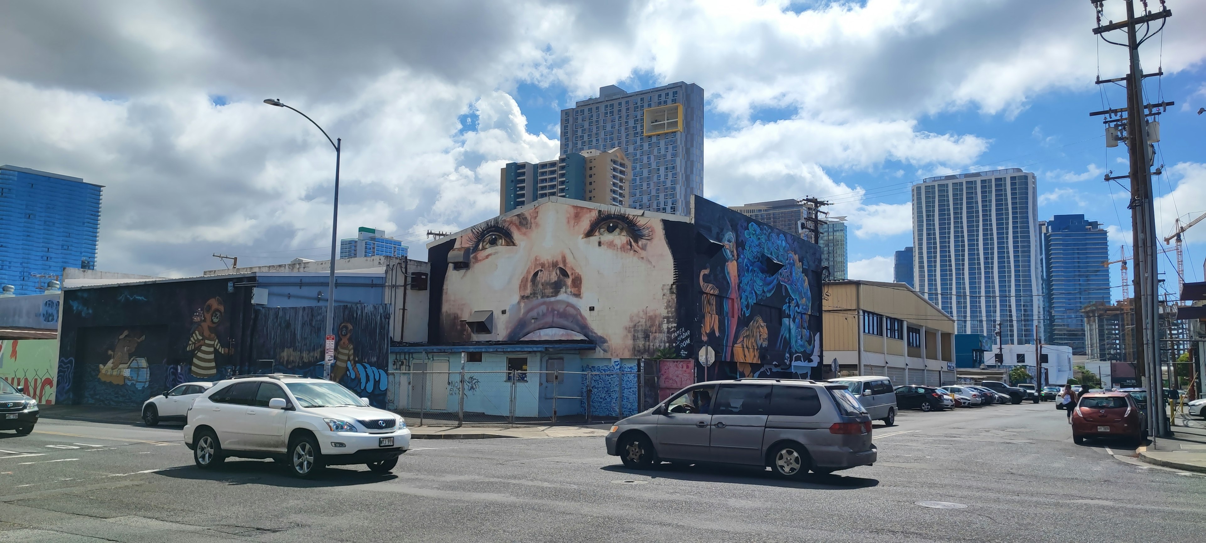 Urban scene featuring a large face mural and skyscrapers