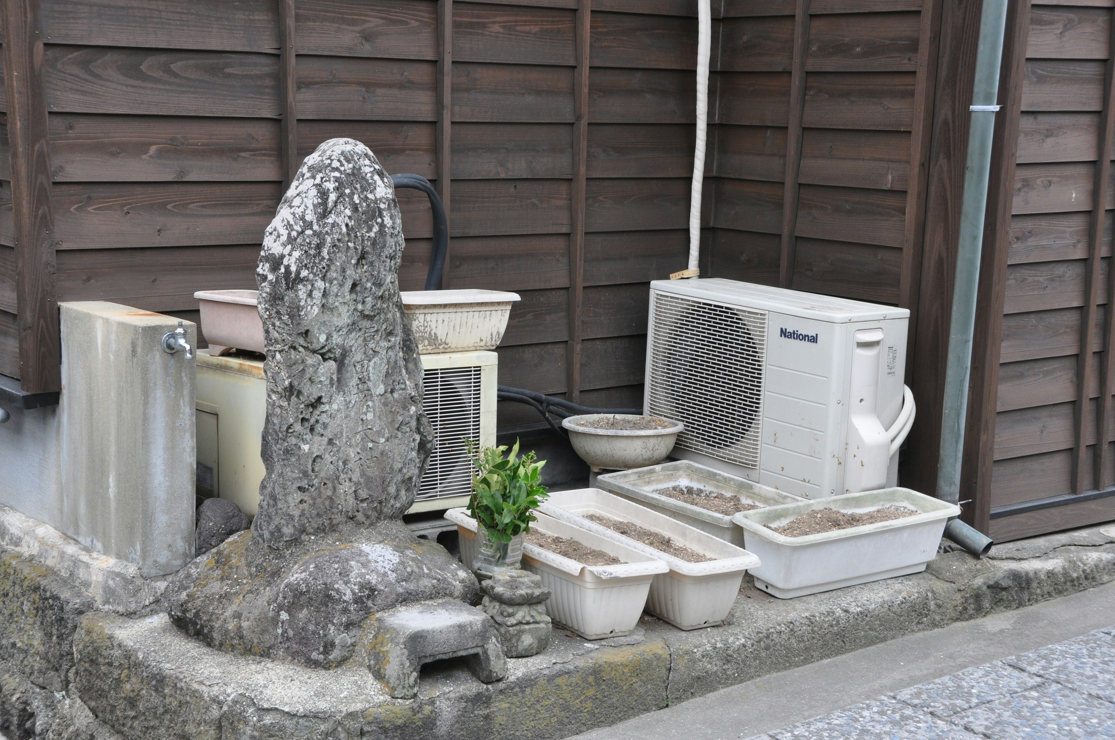 Ein alter Stein und Keramiktöpfe in einer Ecke eines japanischen Gartens