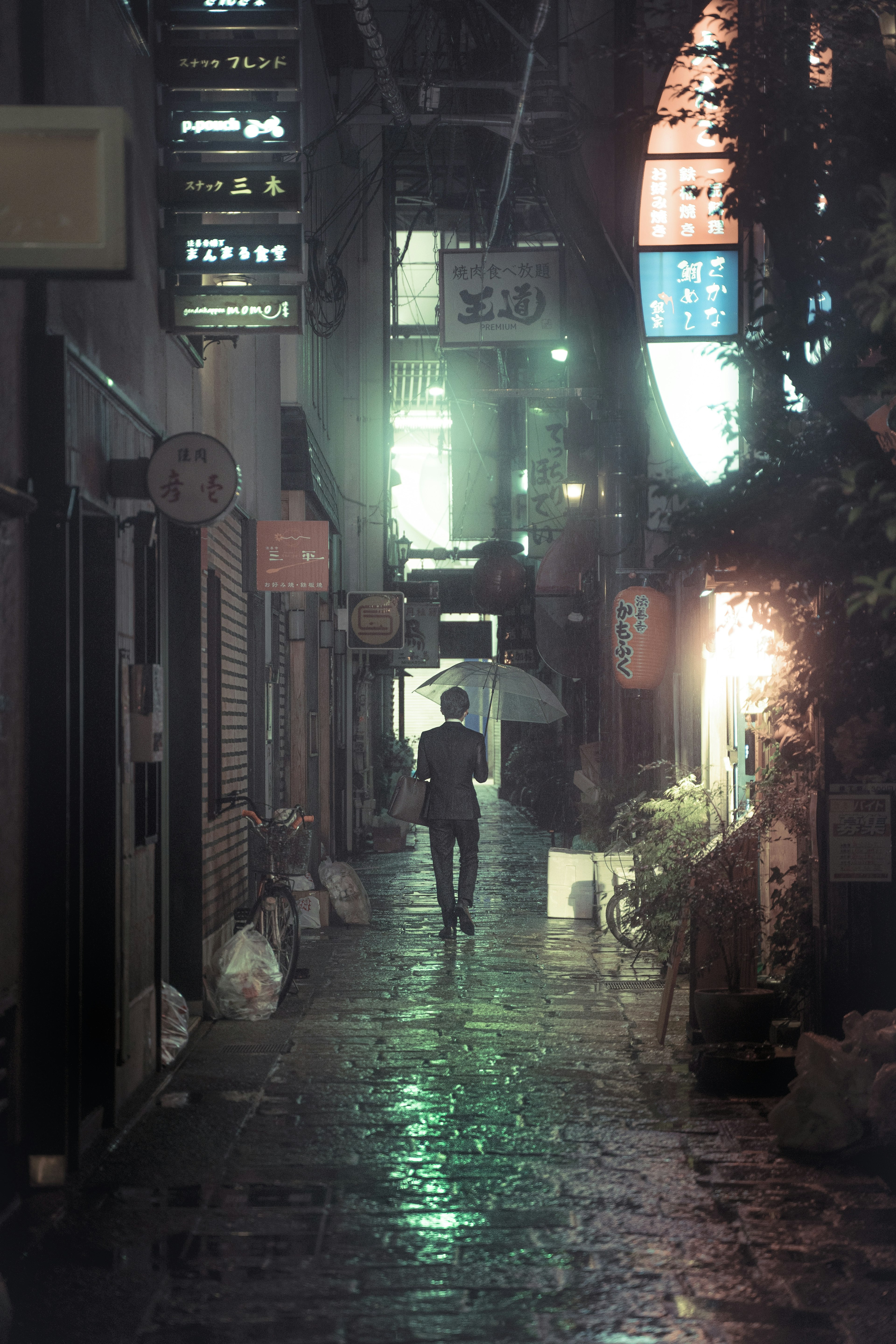 Una persona con un paraguas caminando por un callejón tenuemente iluminado bajo la lluvia