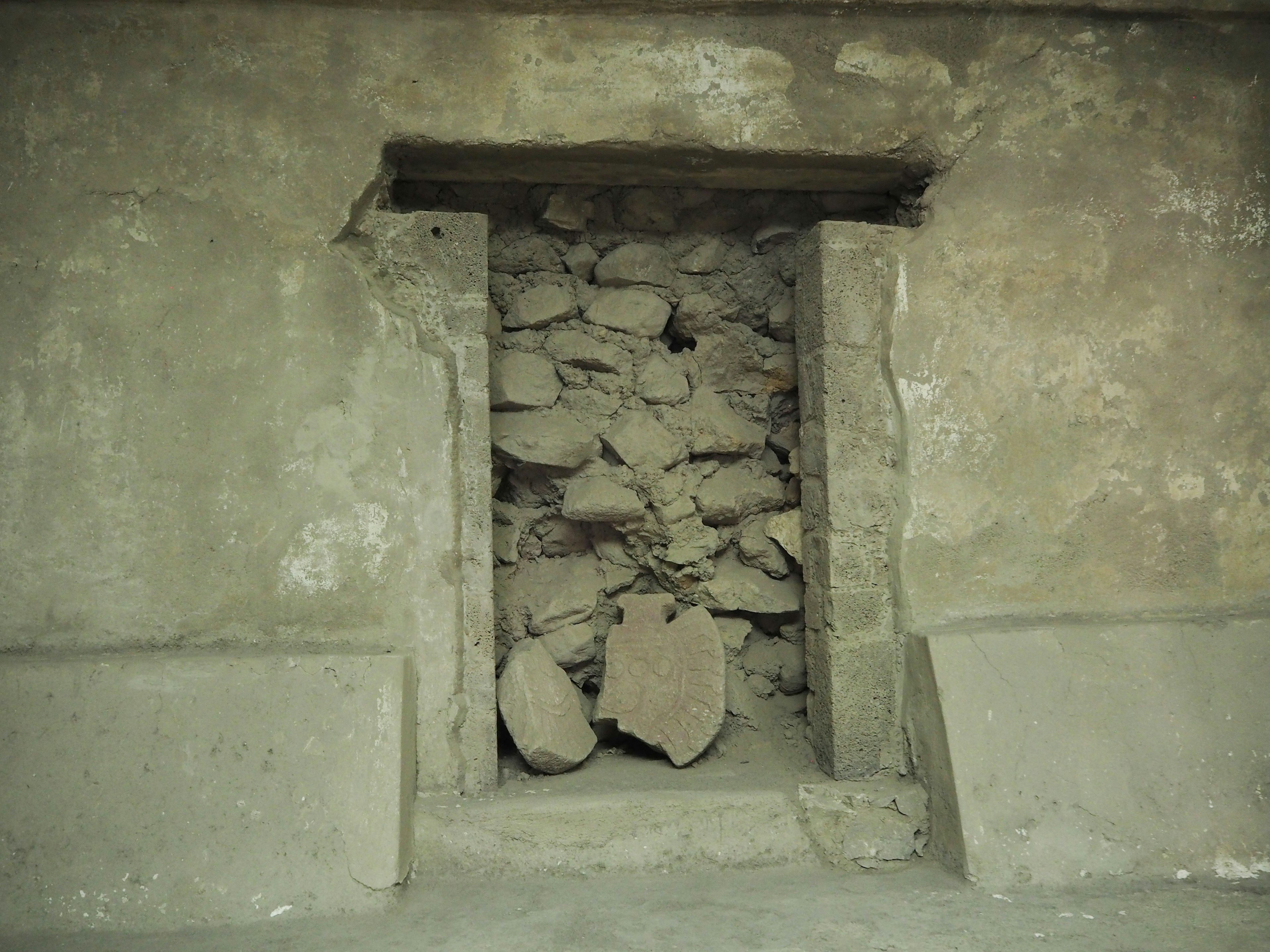 Puerta antigua llena de piedras en una pared desgastada