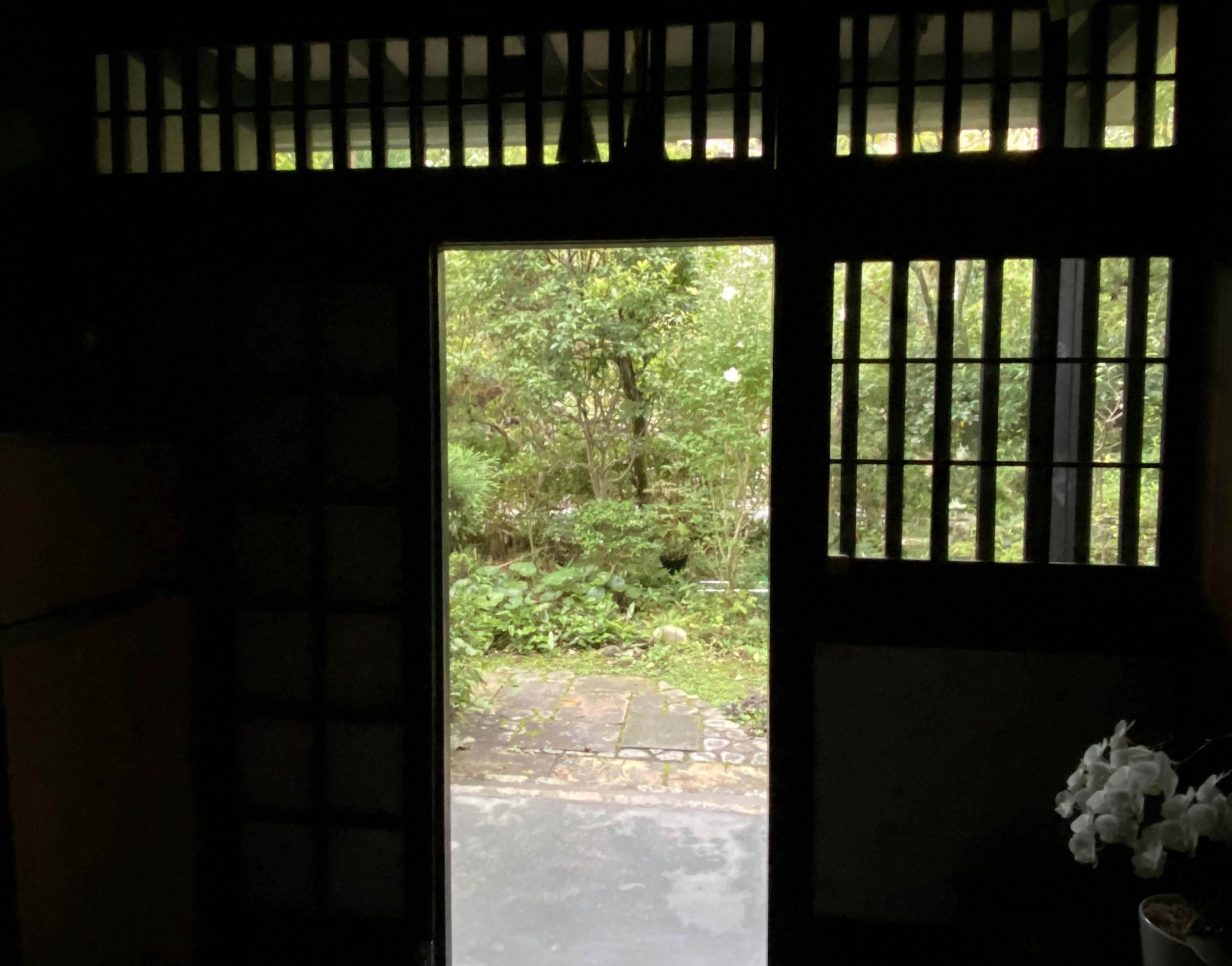 Una puerta de madera se abre a un jardín verde y exuberante creando una vista serena