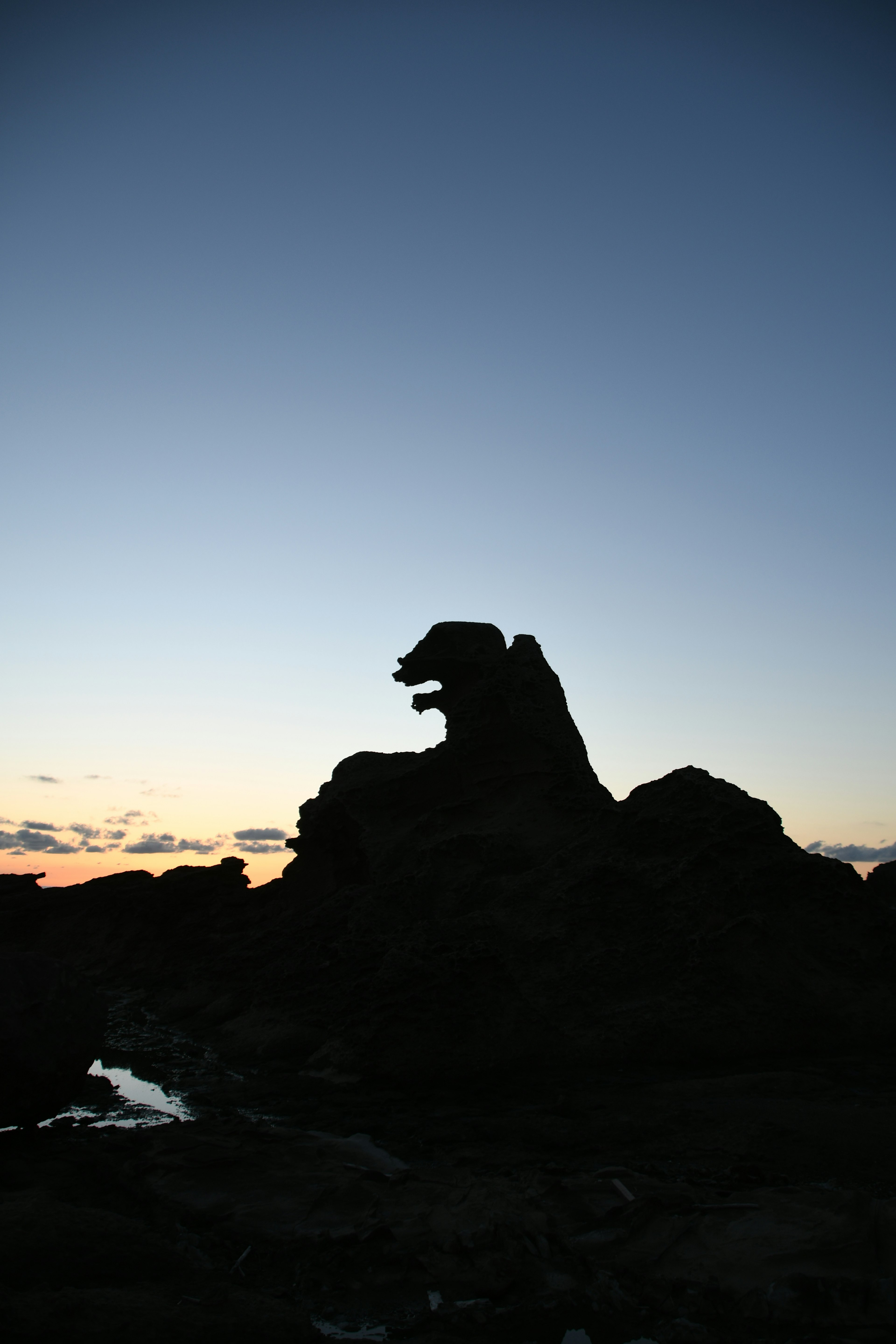 夕暮れ時の岩のシルエットが獅子のように見える風景