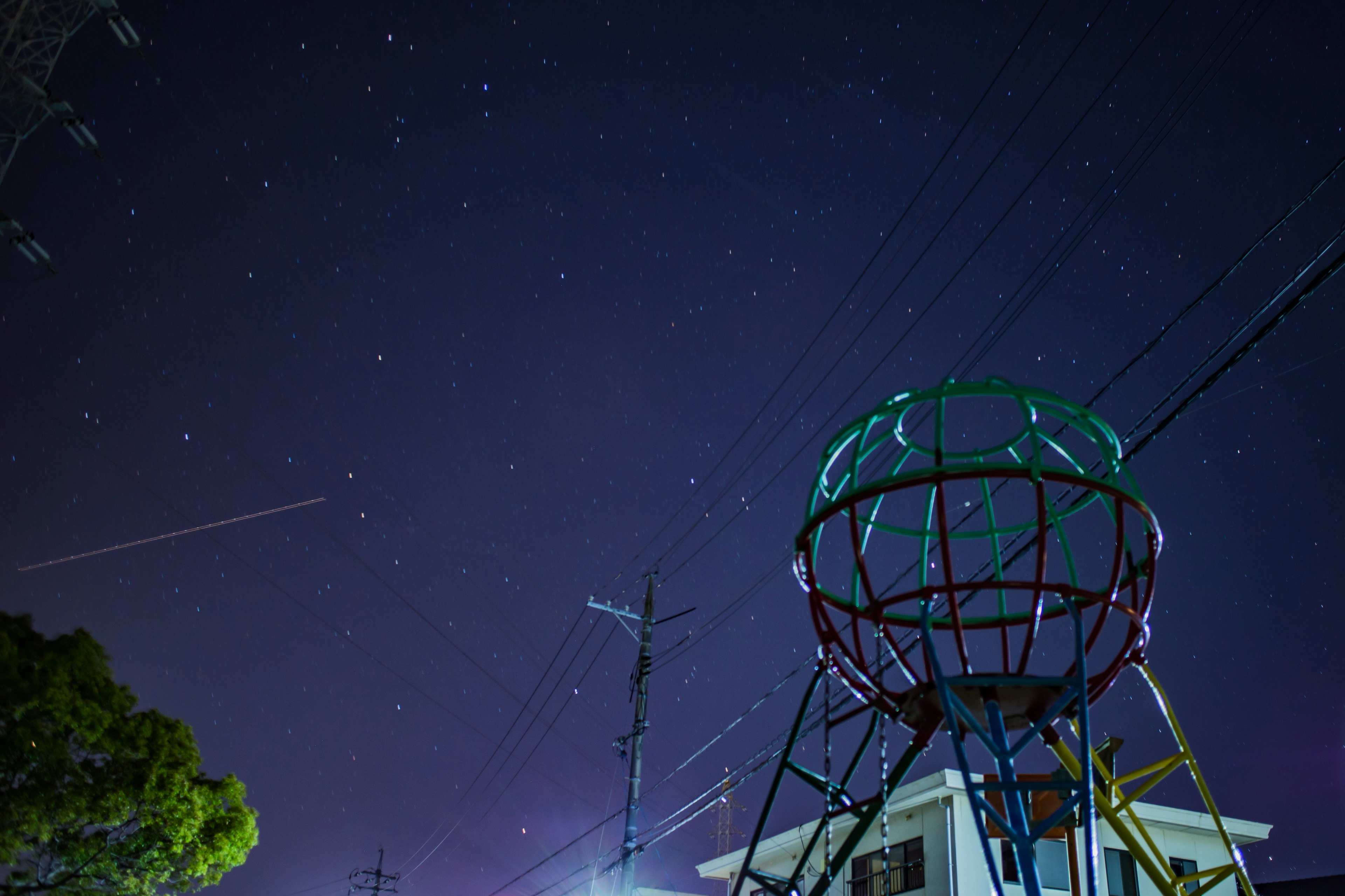 Struttura colorata sotto un cielo stellato con un edificio visibile