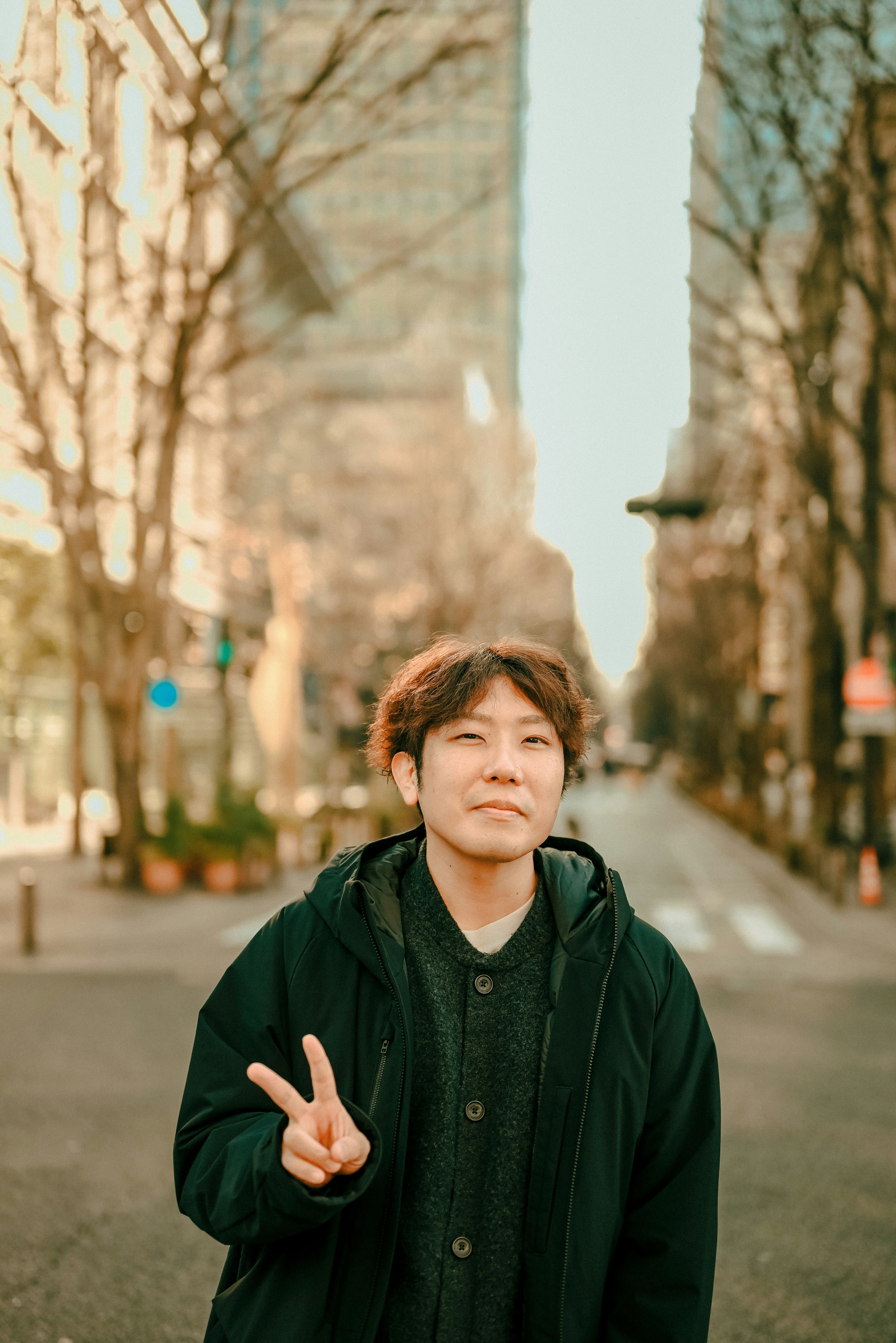 Young man making peace sign on a city street