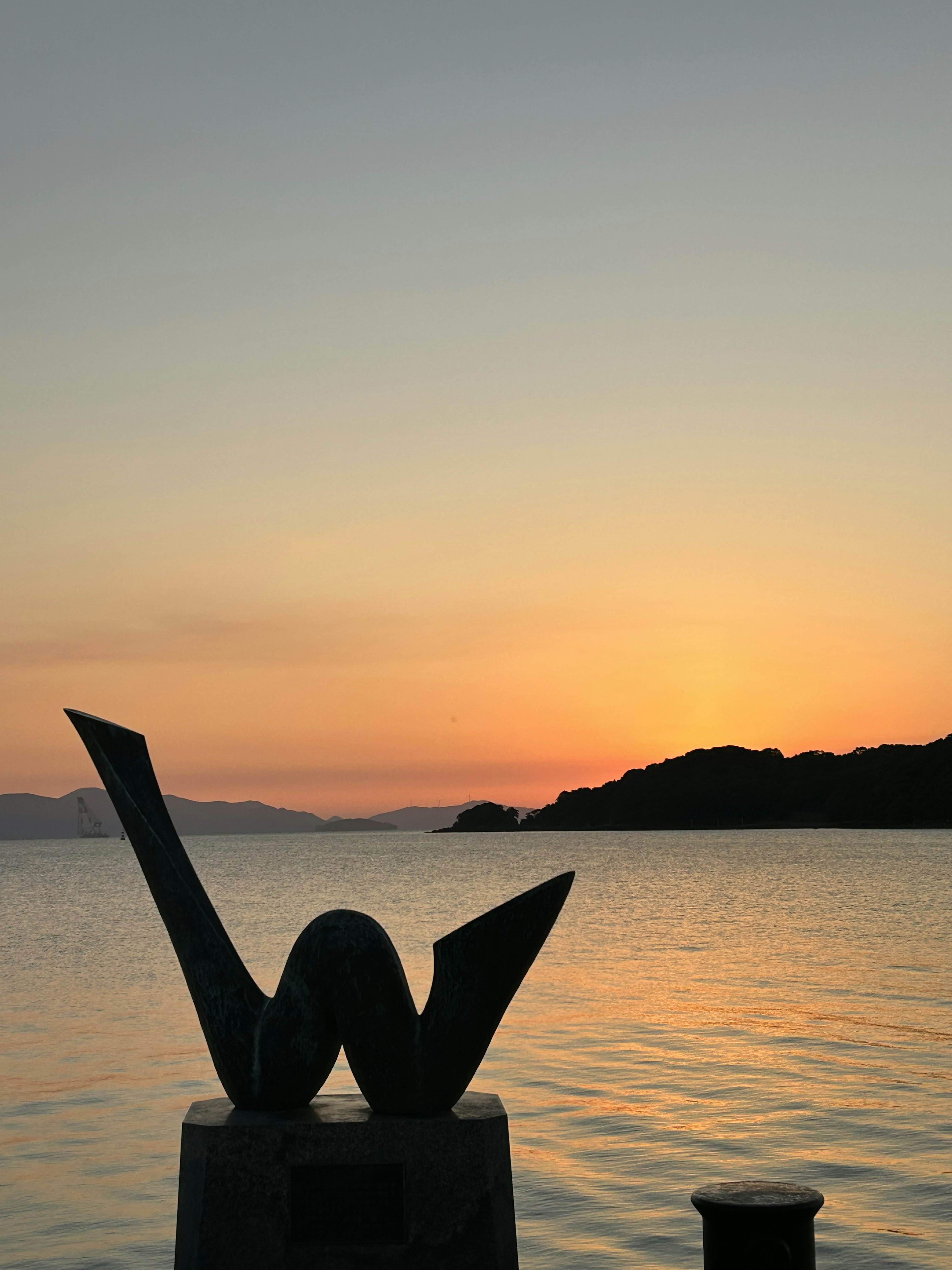 Sculpture by the water with sunset backdrop