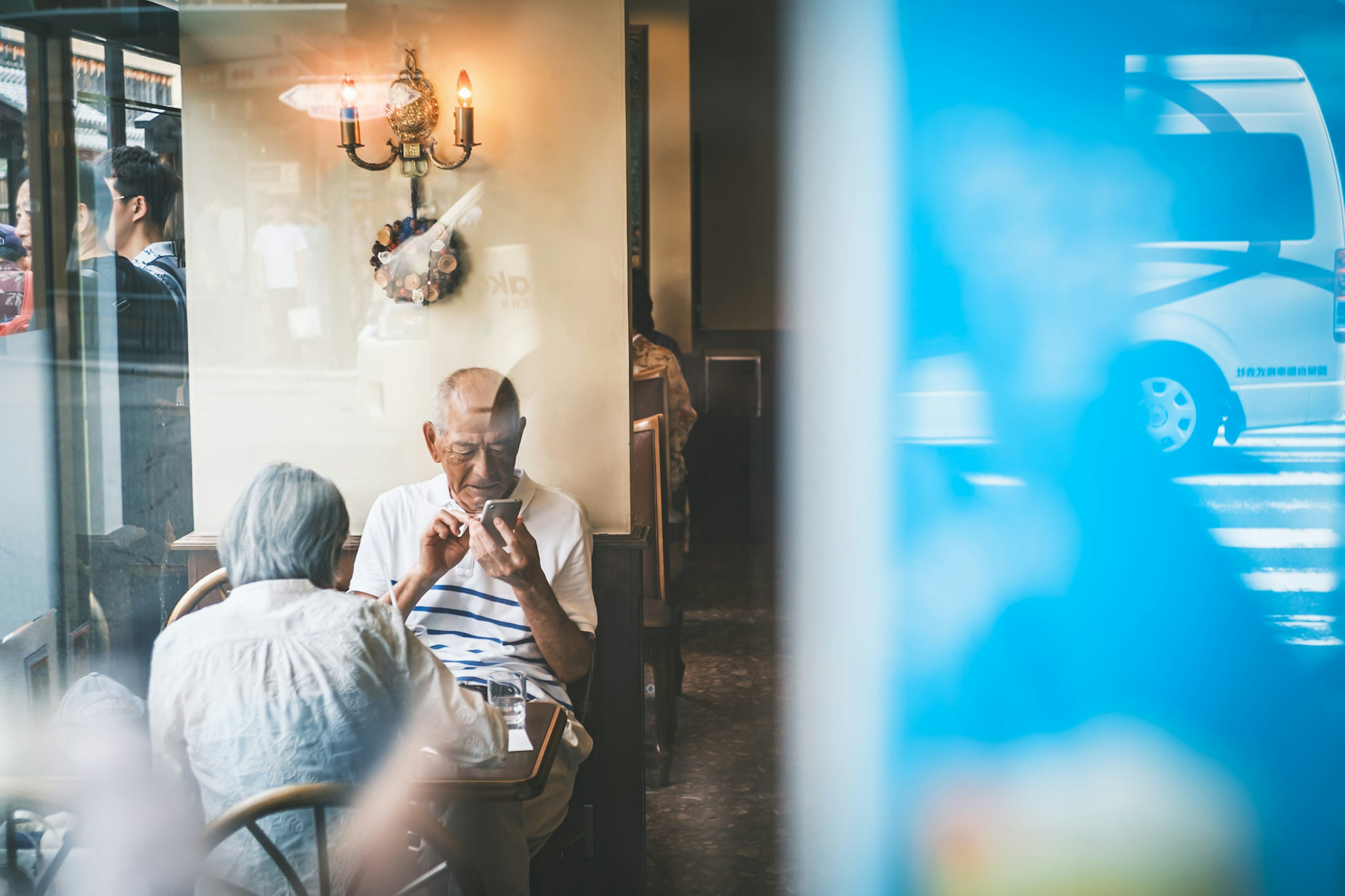 Ältere Menschen, die in einem Café sitzen, durch ein Fenster mit sanfter Beleuchtung sichtbar