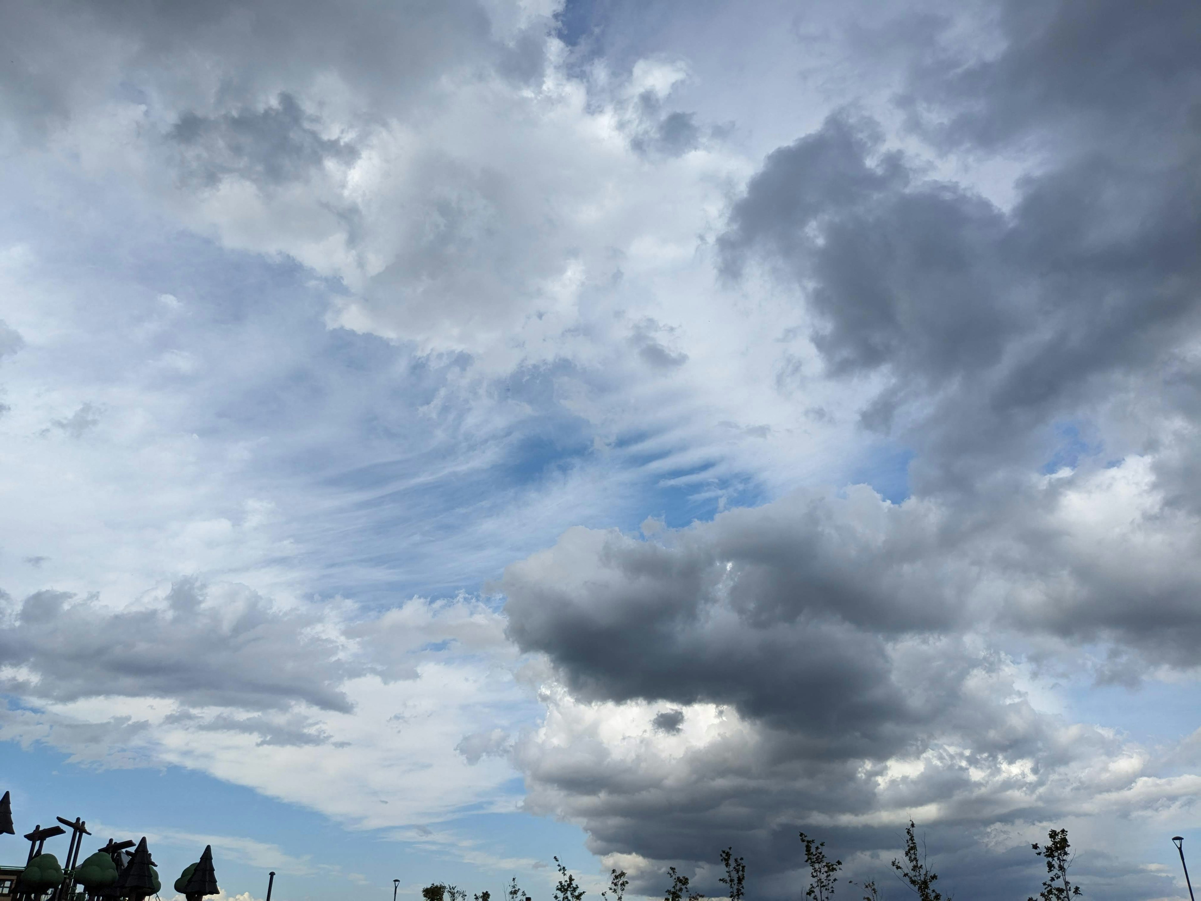 青い空と白い雲が広がる風景に、灰色の雲が重なり合う