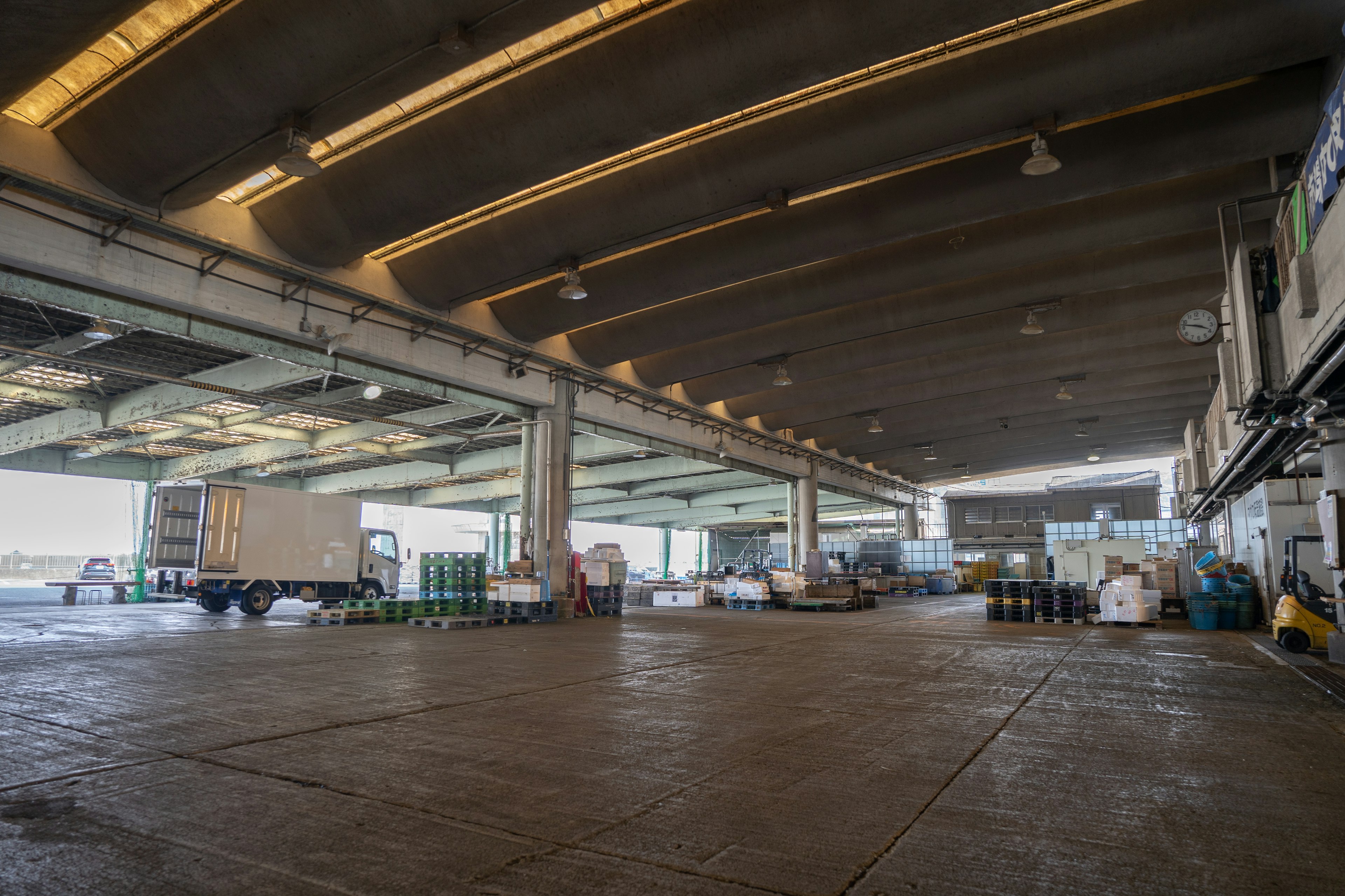 Intérieur spacieux d'un entrepôt avec un camion et des palettes visibles