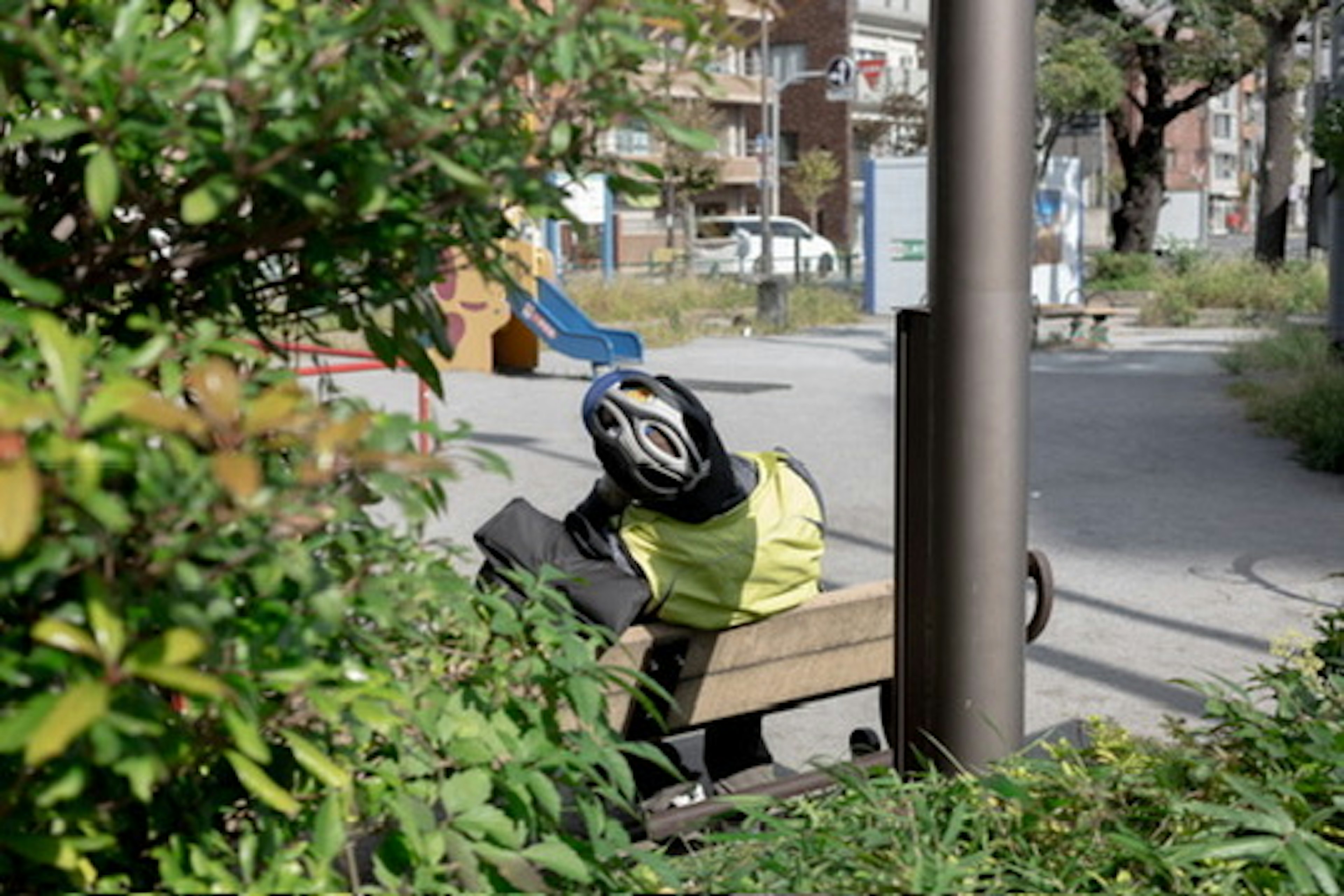 Una persona con casco de bicicleta sentada en un banco del parque