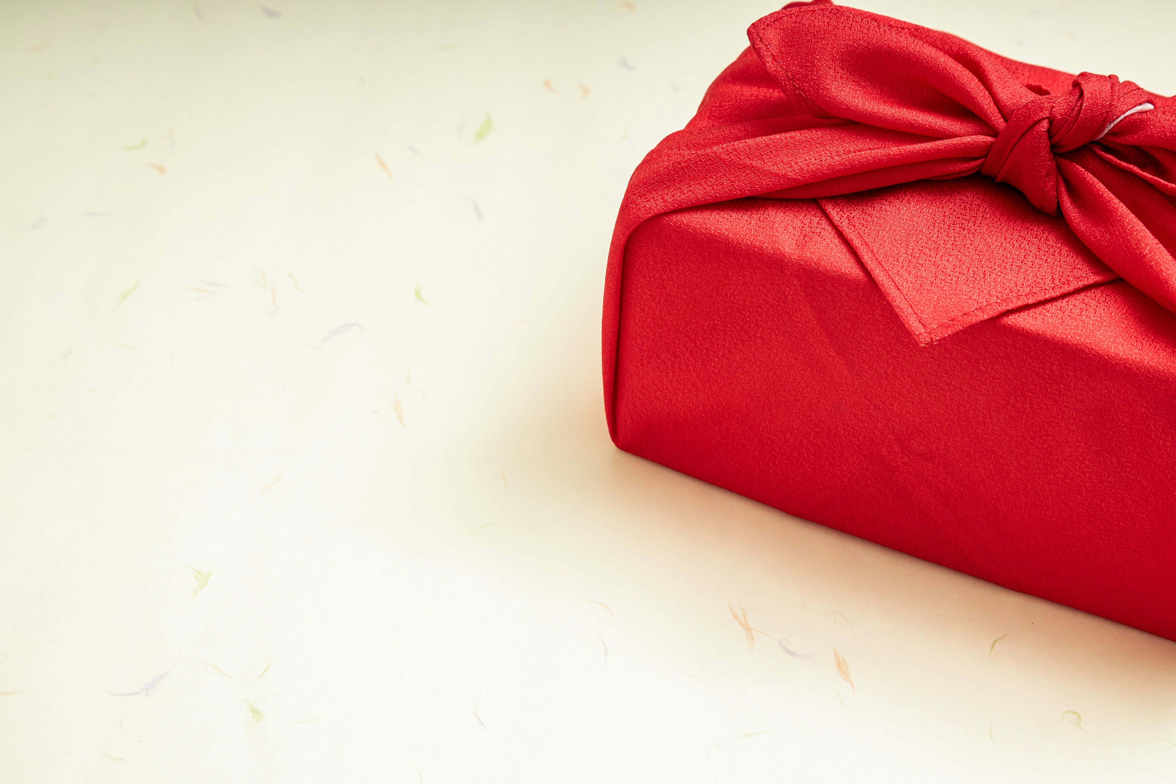 A red gift wrapped with a bow on a light surface