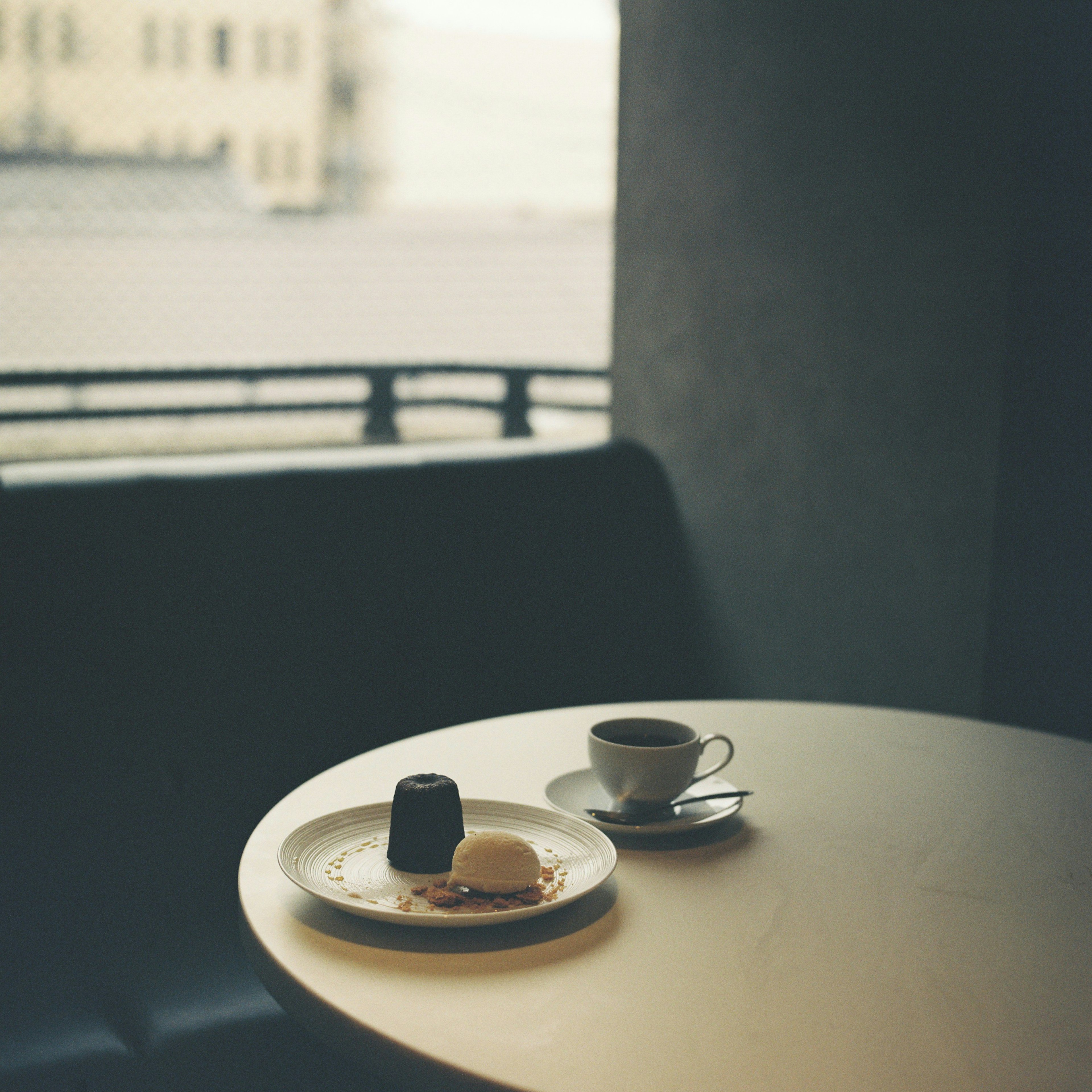 Une tasse de café et une assiette de dessert sur une table avec une vue extérieure