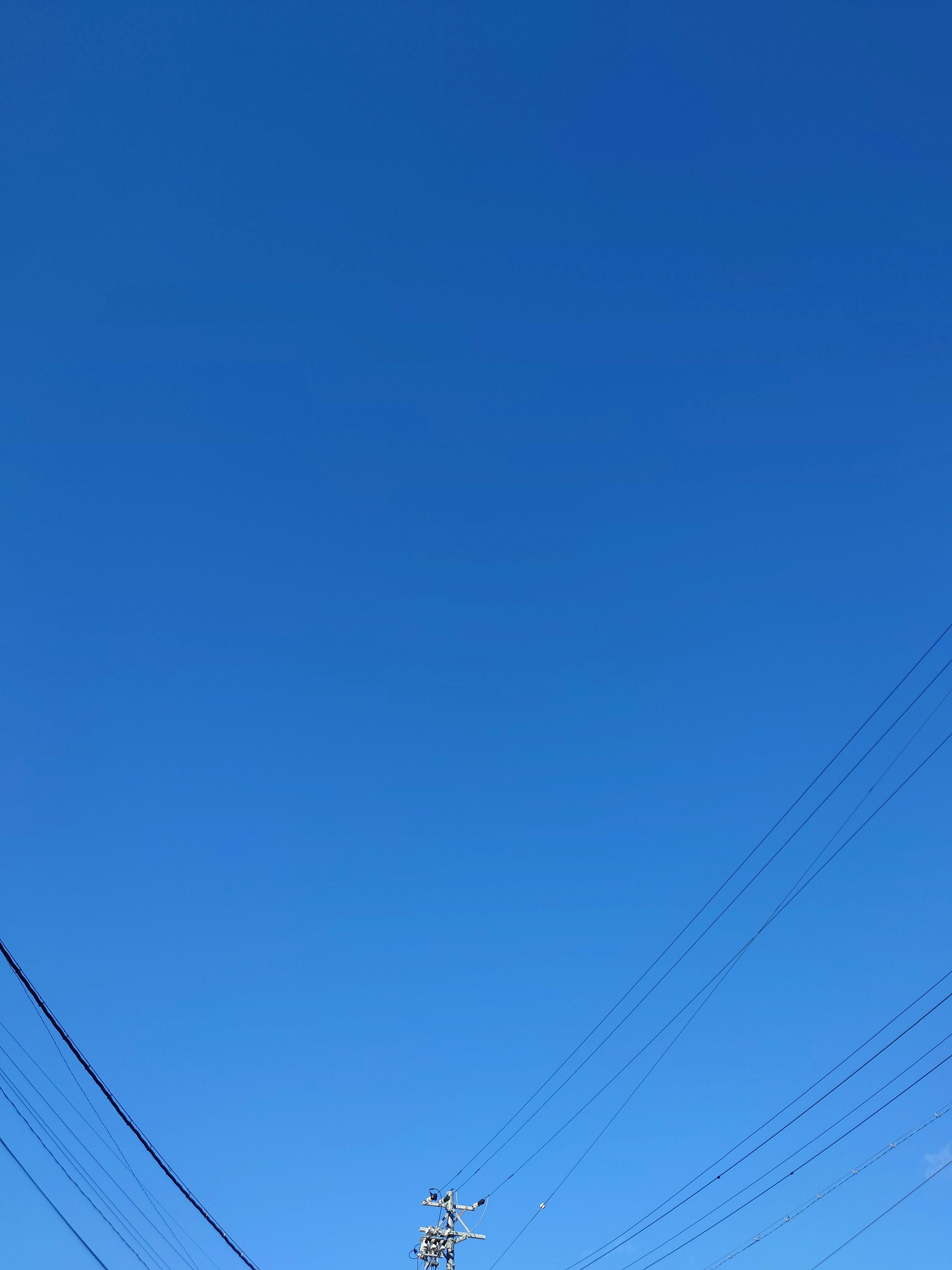 Heller blauer Himmel mit sichtbaren Stromleitungen