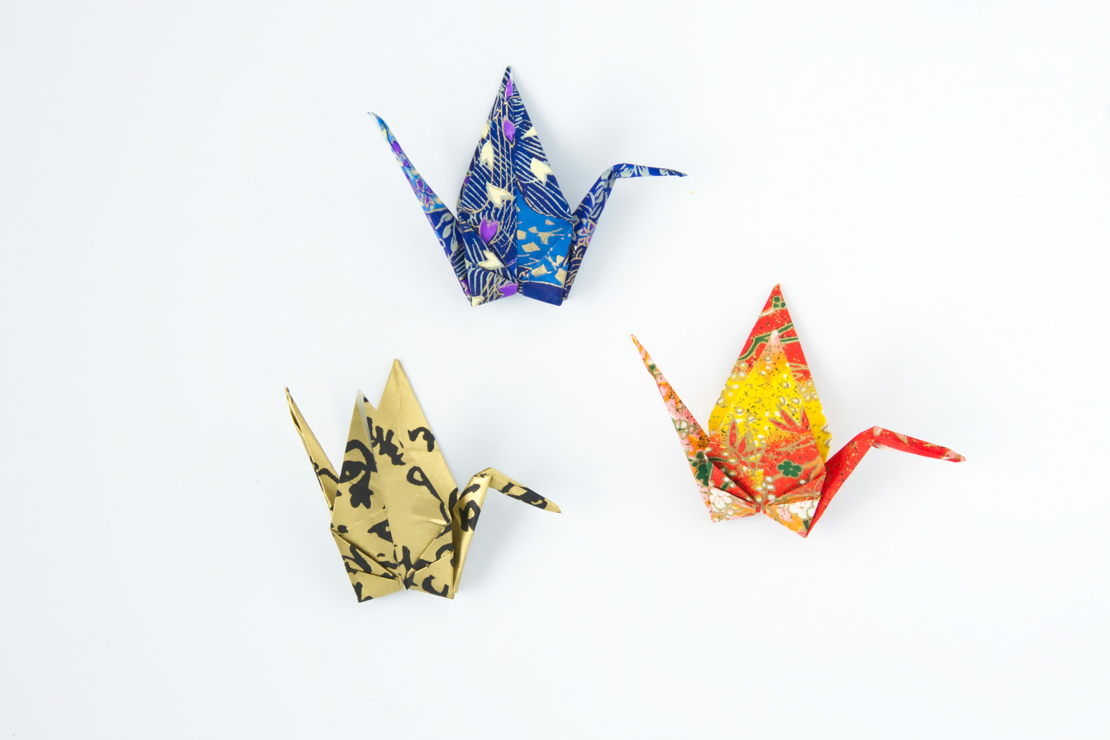 Three colorful origami cranes arranged on a white background