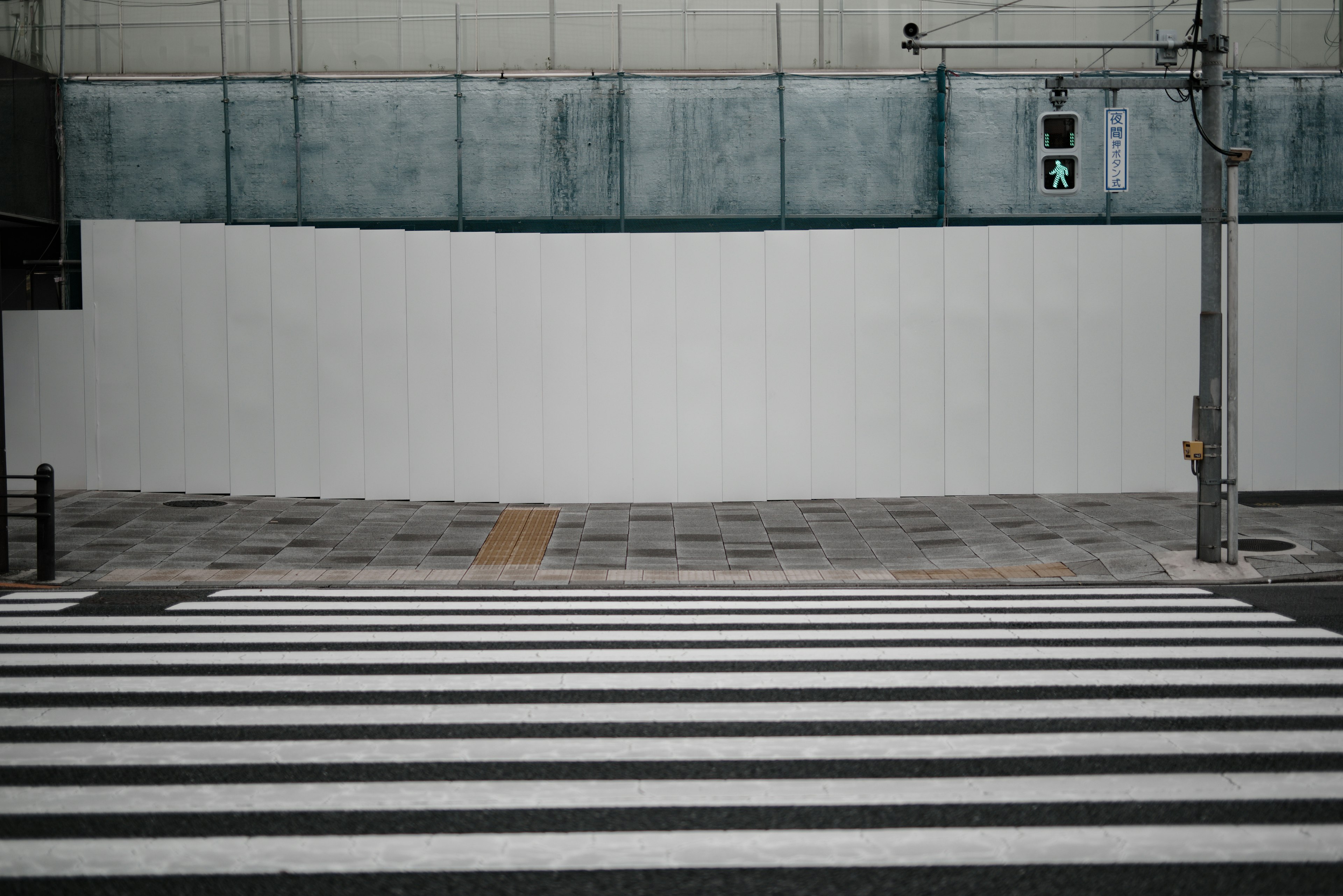 Crosswalk with a white wall in the background and traffic light