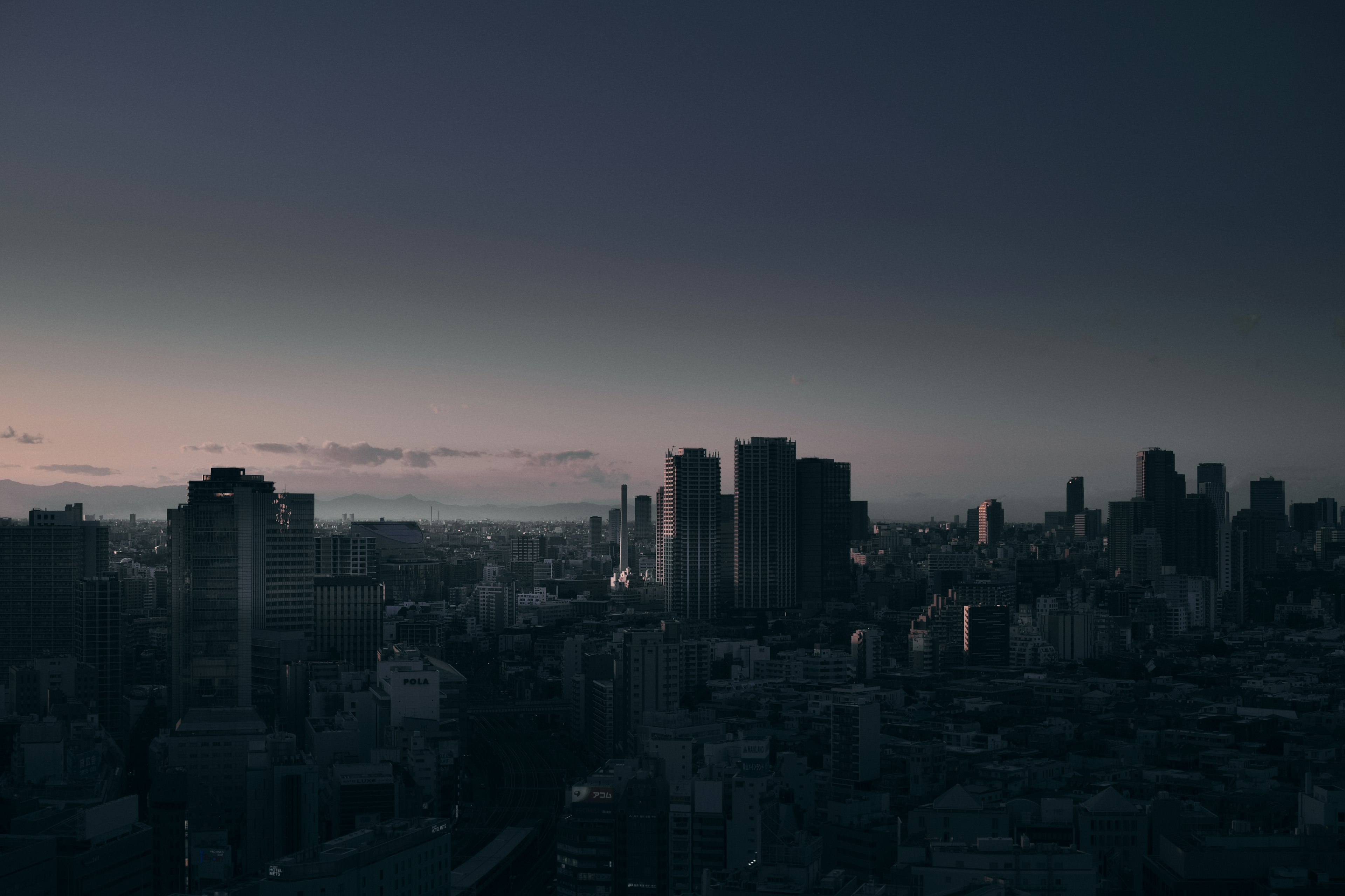 City skyline at dusk with dark buildings and fading light