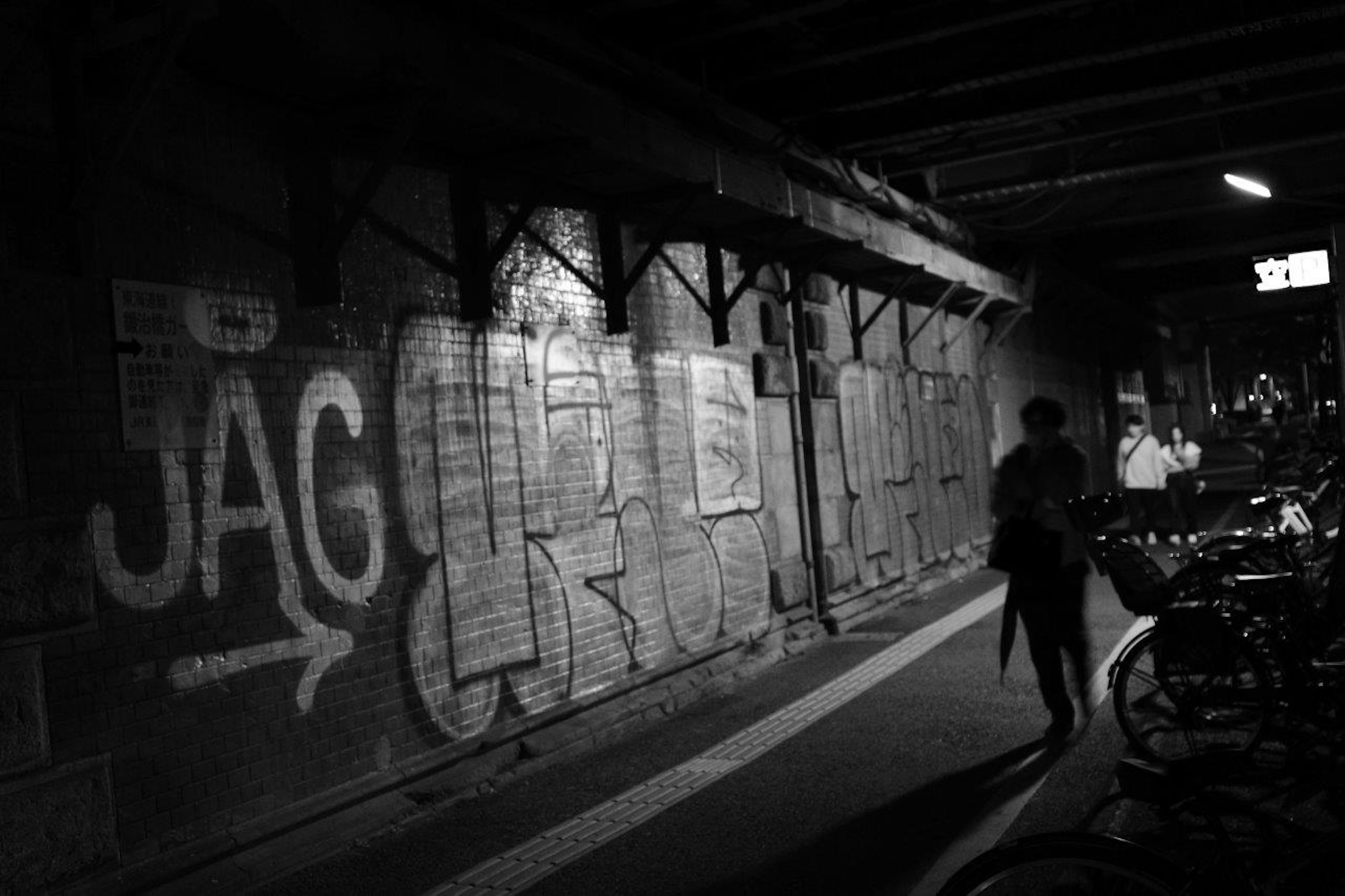 Image featuring graffiti on a dark corridor with bicycles