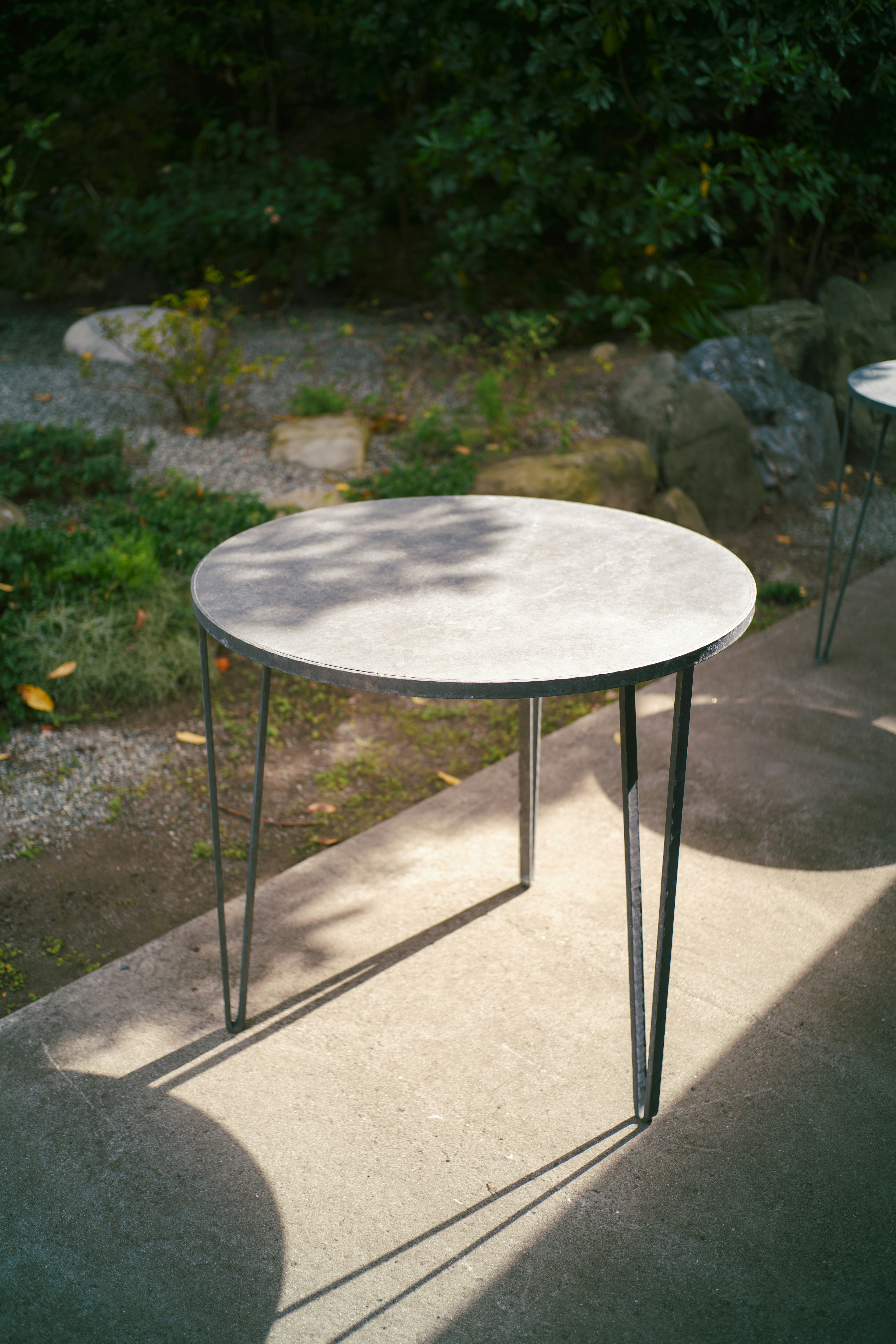 Round concrete table with slender metal legs in an outdoor setting