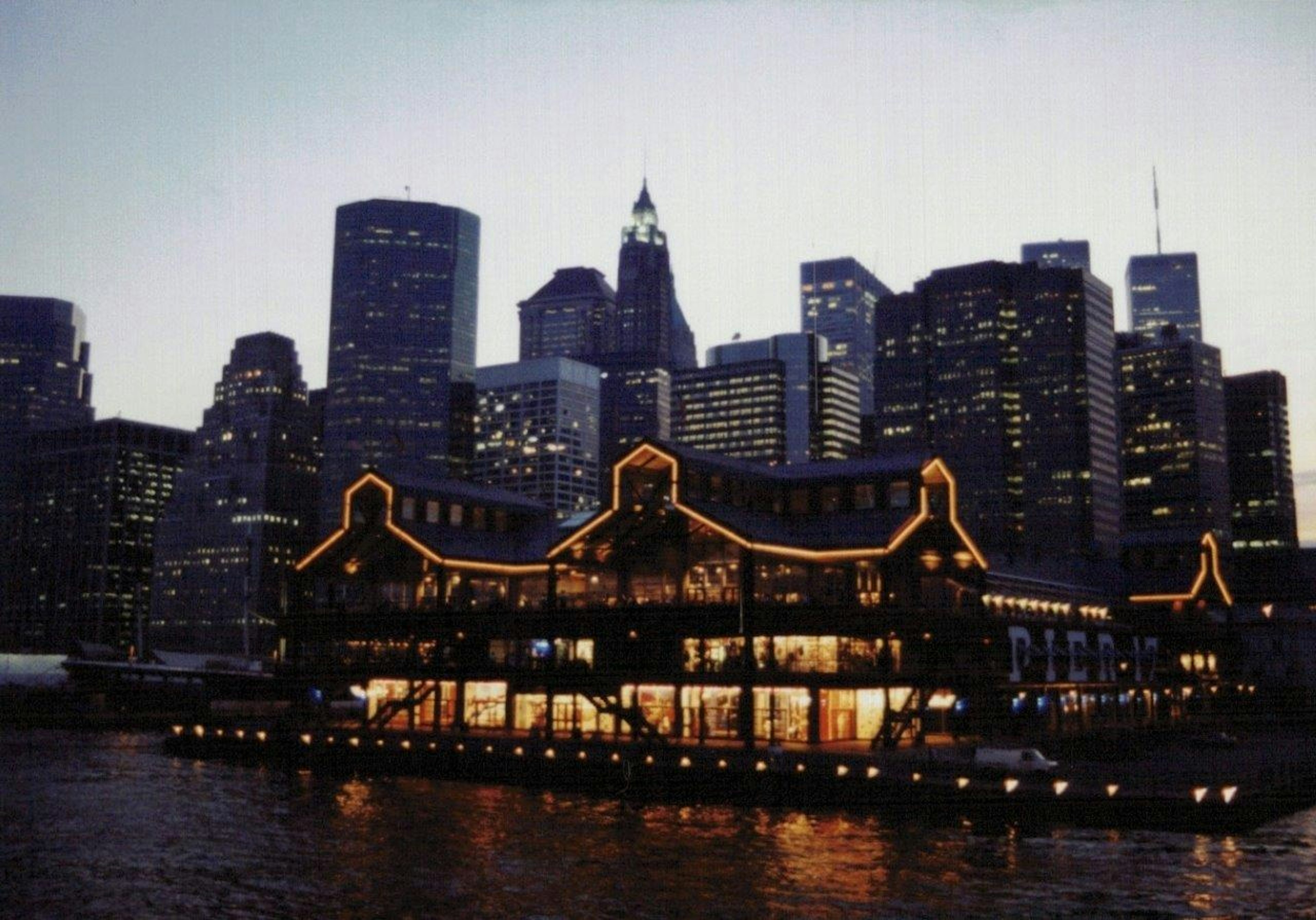 Horizonte de Nueva York al anochecer con edificio iluminado en la costa