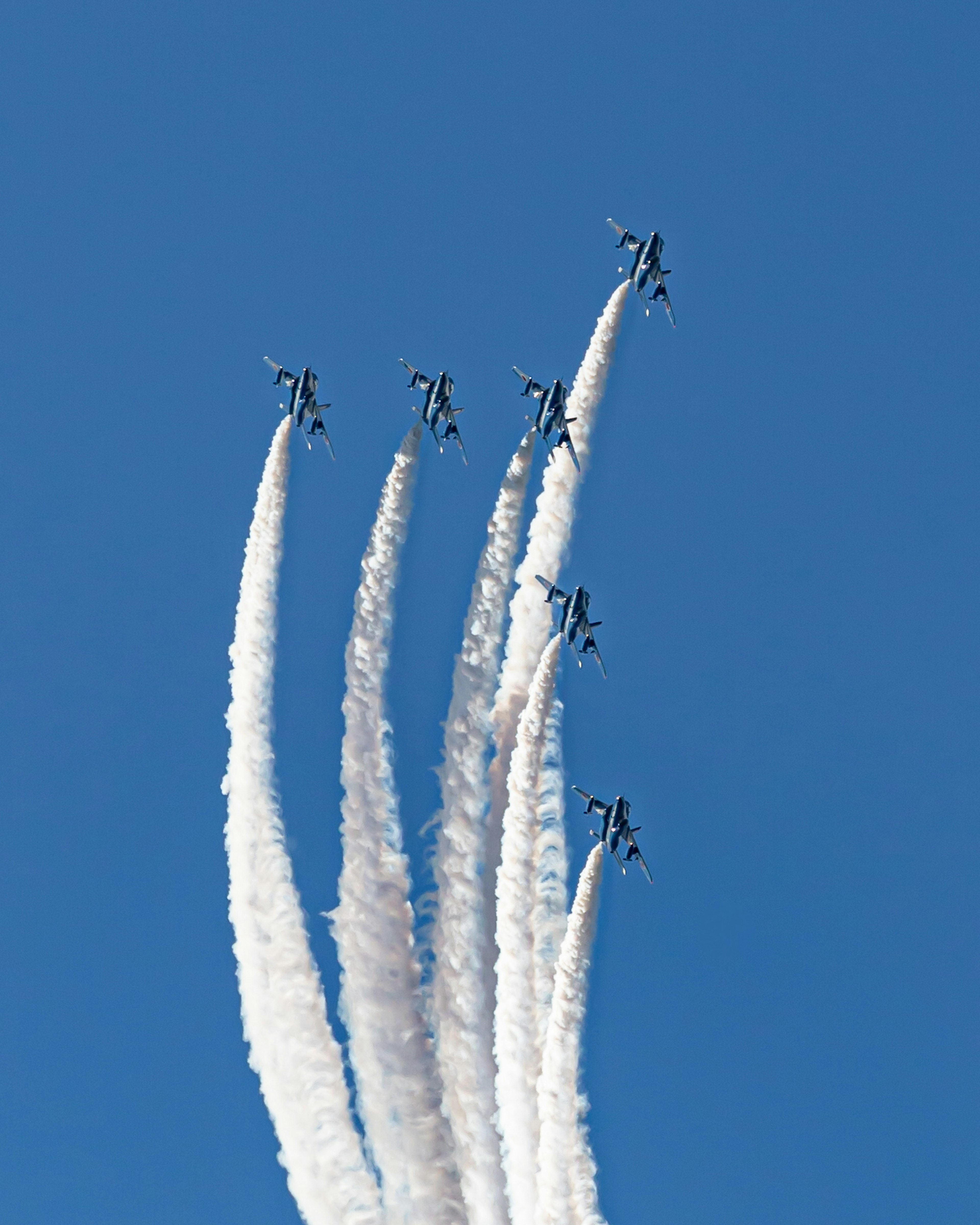 青空を背景にした航空機のスモークトレイルが見える