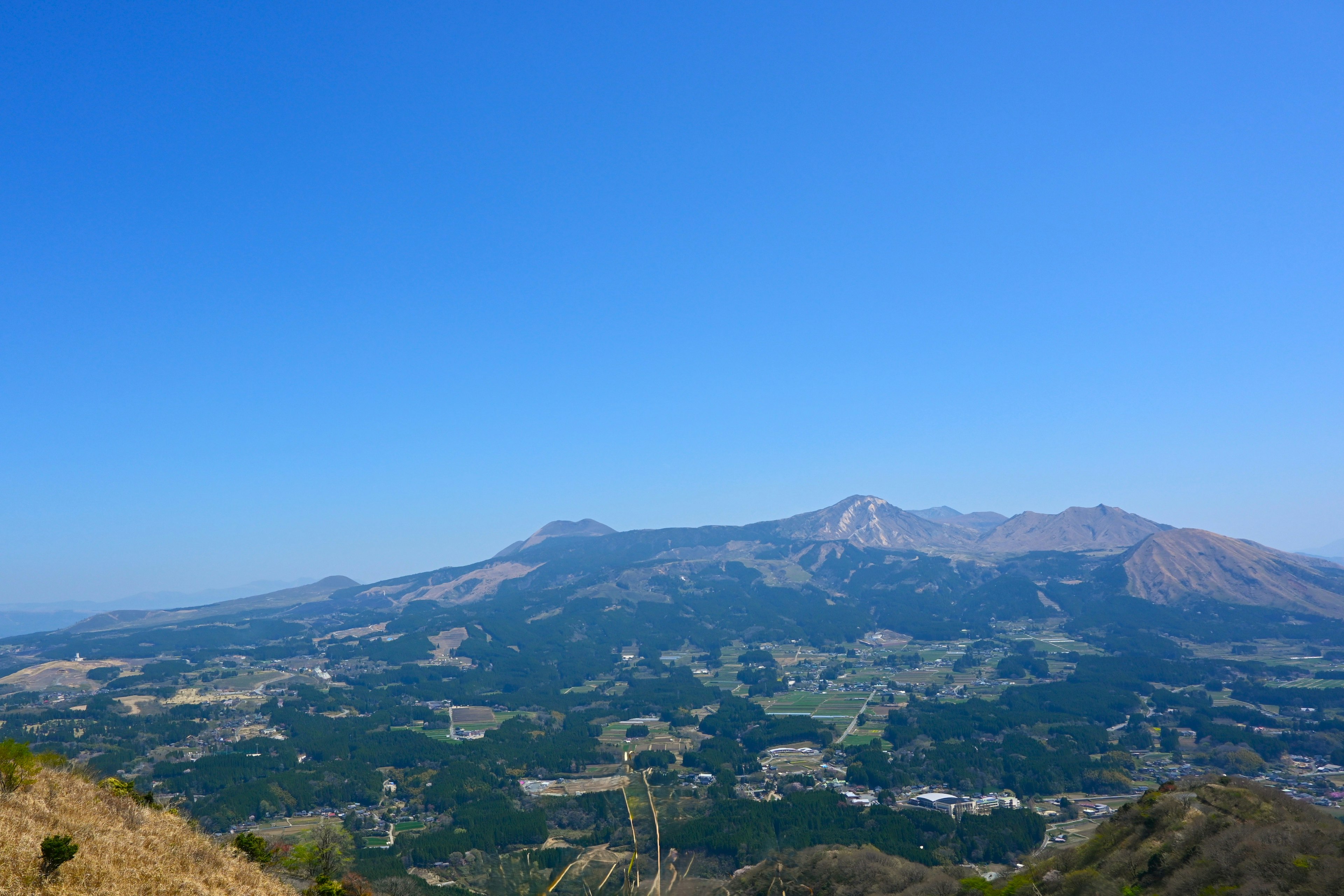 Vista panoramica di montagne e valli verdi sotto un cielo blu chiaro