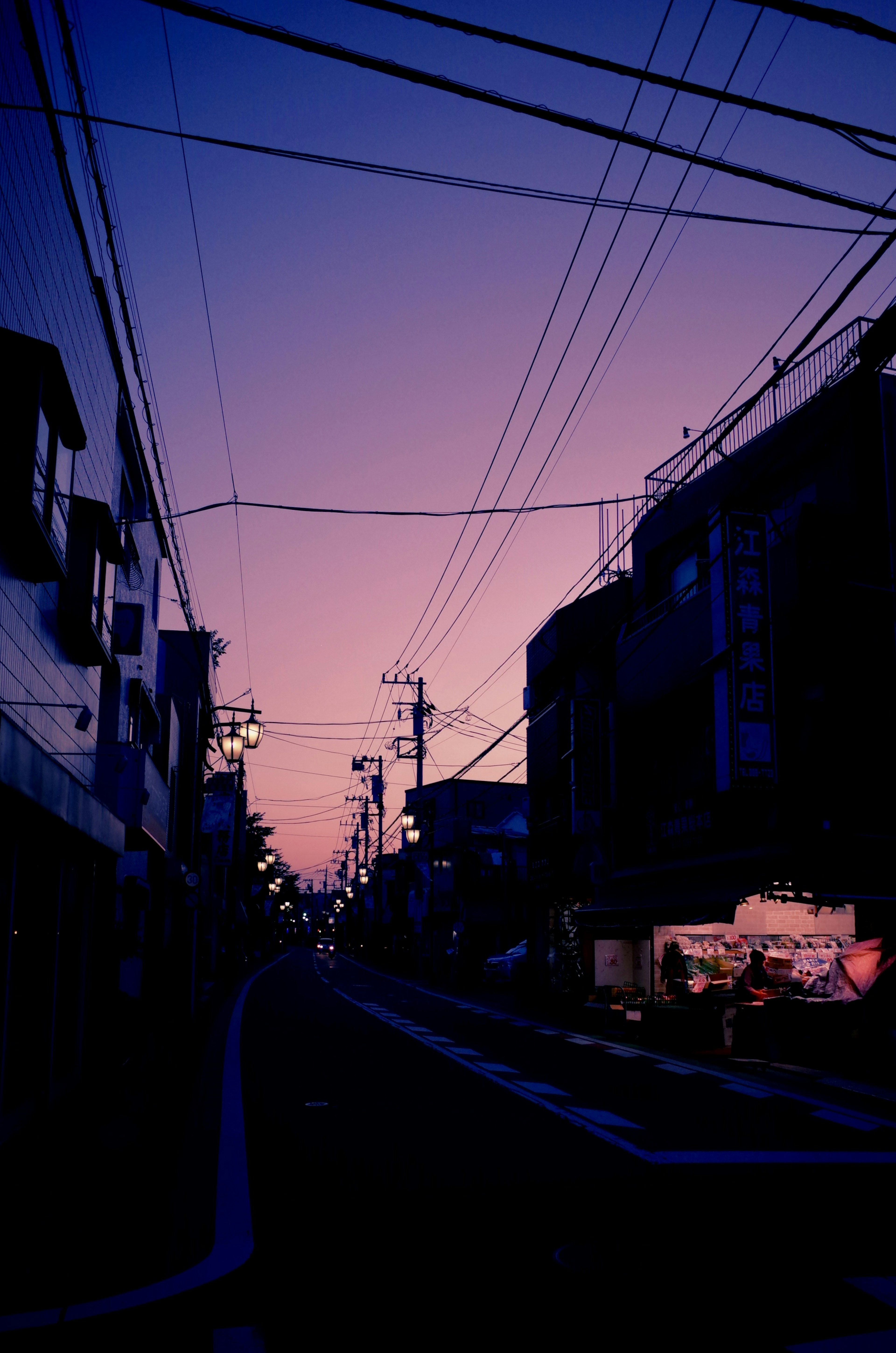 Street scene at dusk with intersecting power lines and soft purple hues