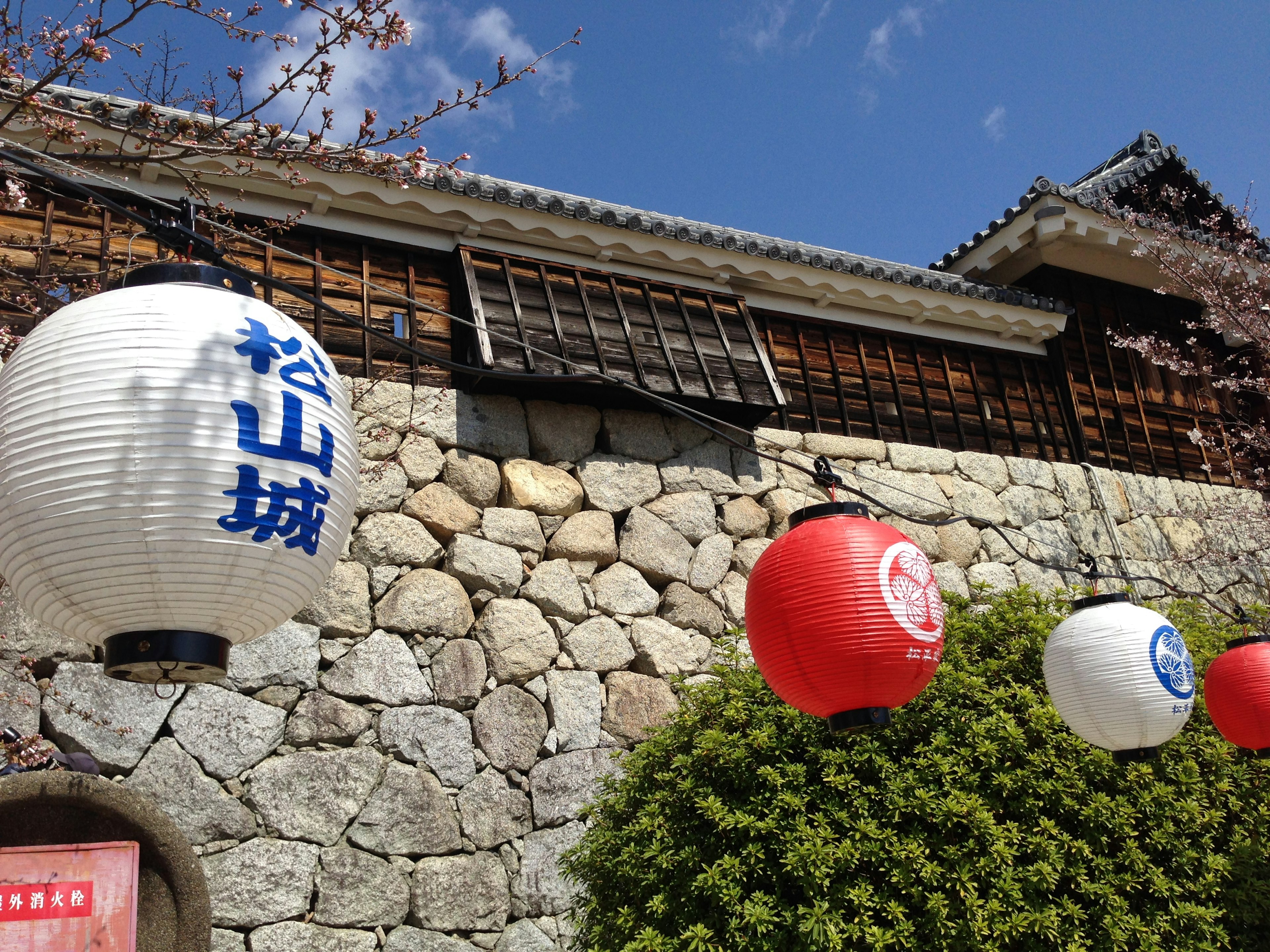 Blick auf die Steinmauer von Matsuyama Castle mit Laternen