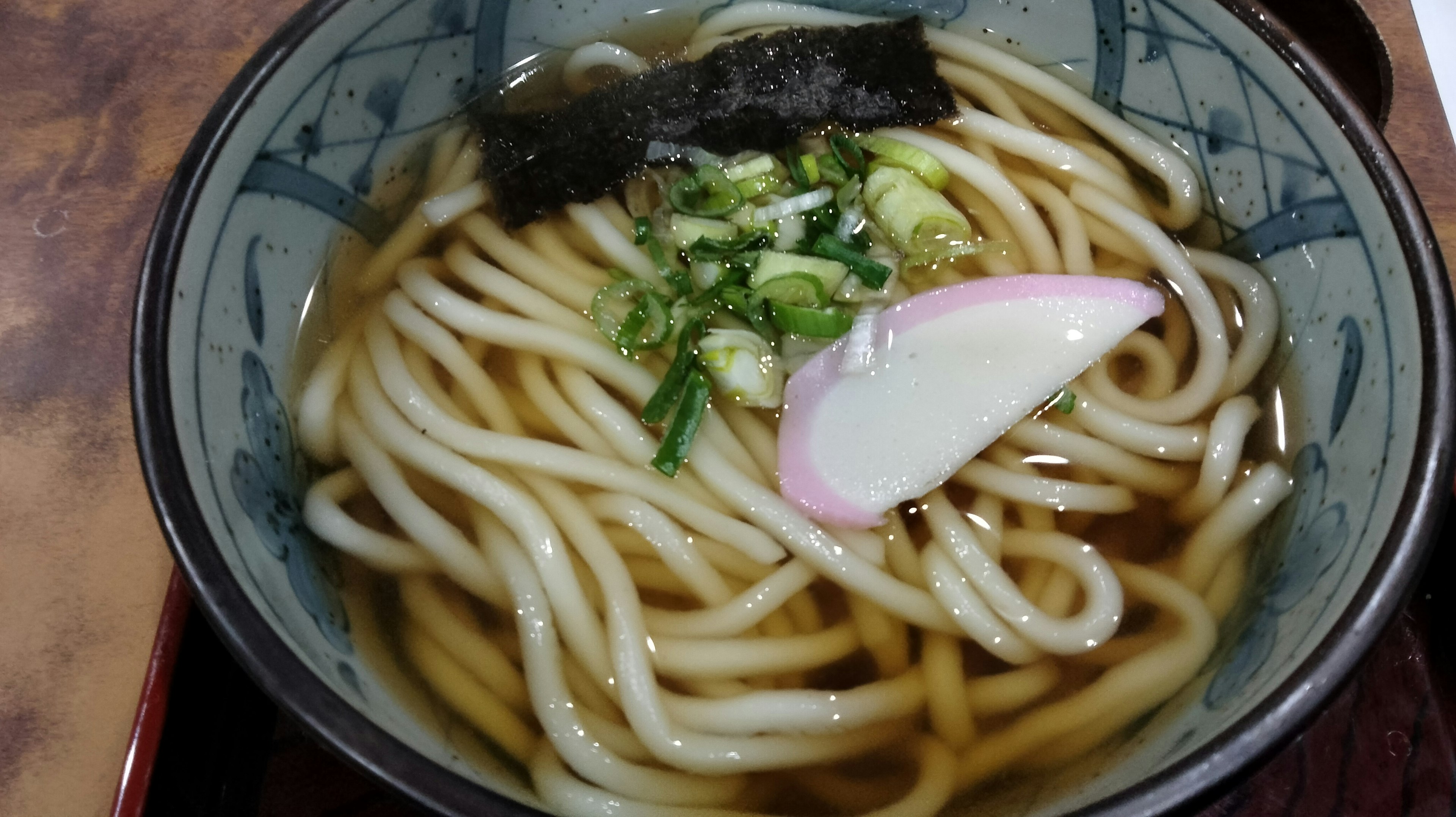 Bowl of udon noodles with broth green onions fish cake and seaweed