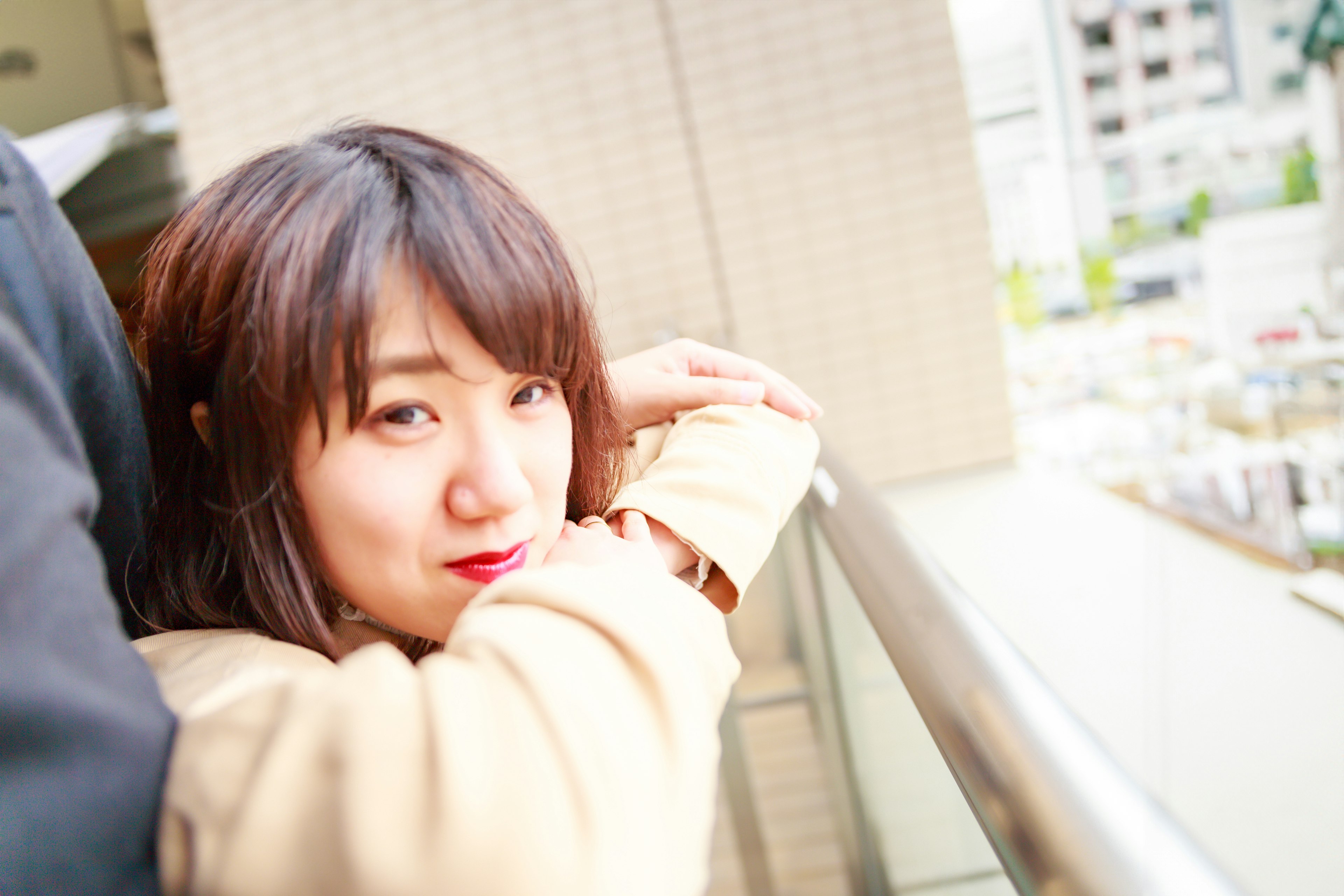 A woman leaning on a railing with a cityscape in the background