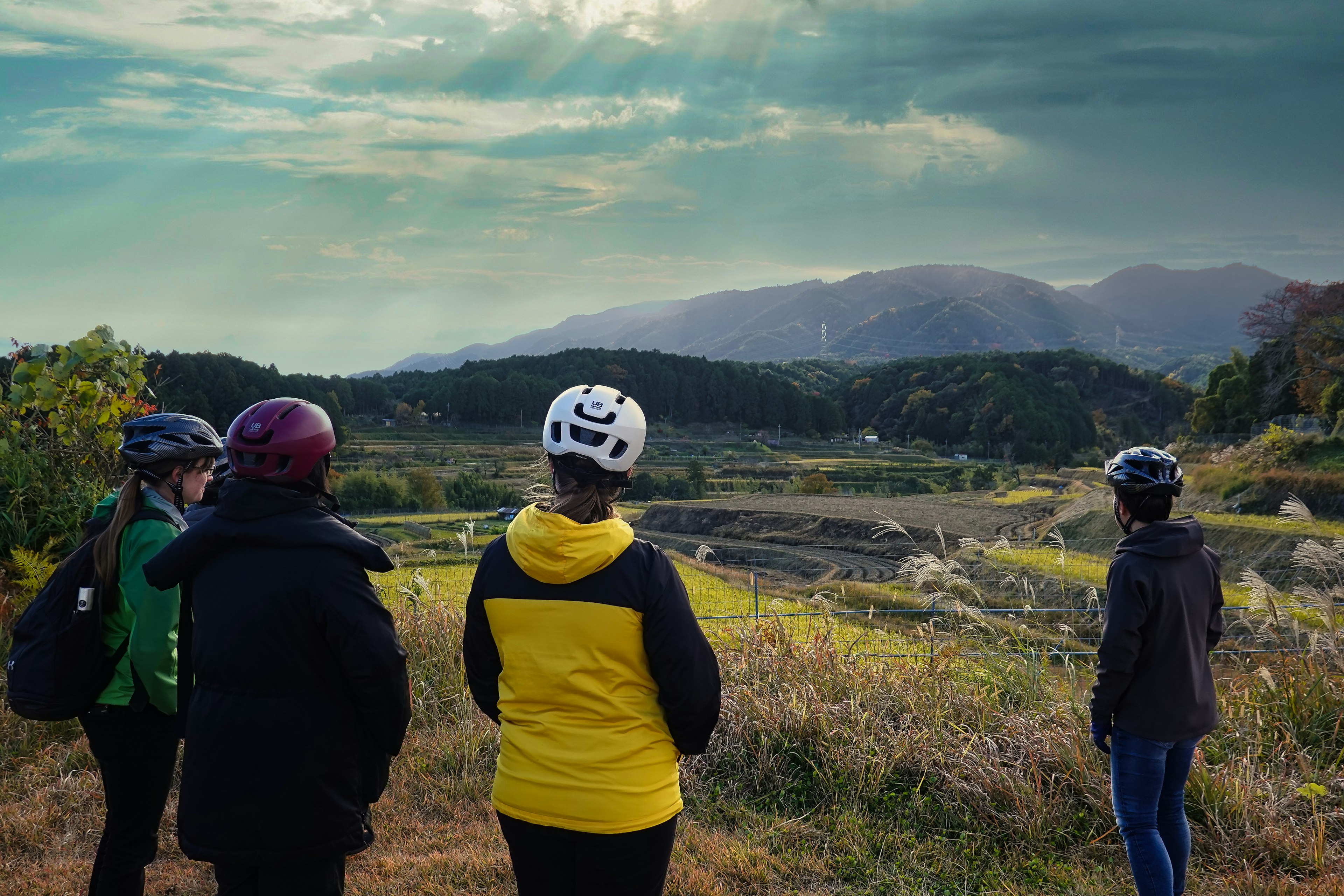 サイクリングヘルメットをかぶったグループが山の風景を眺めている