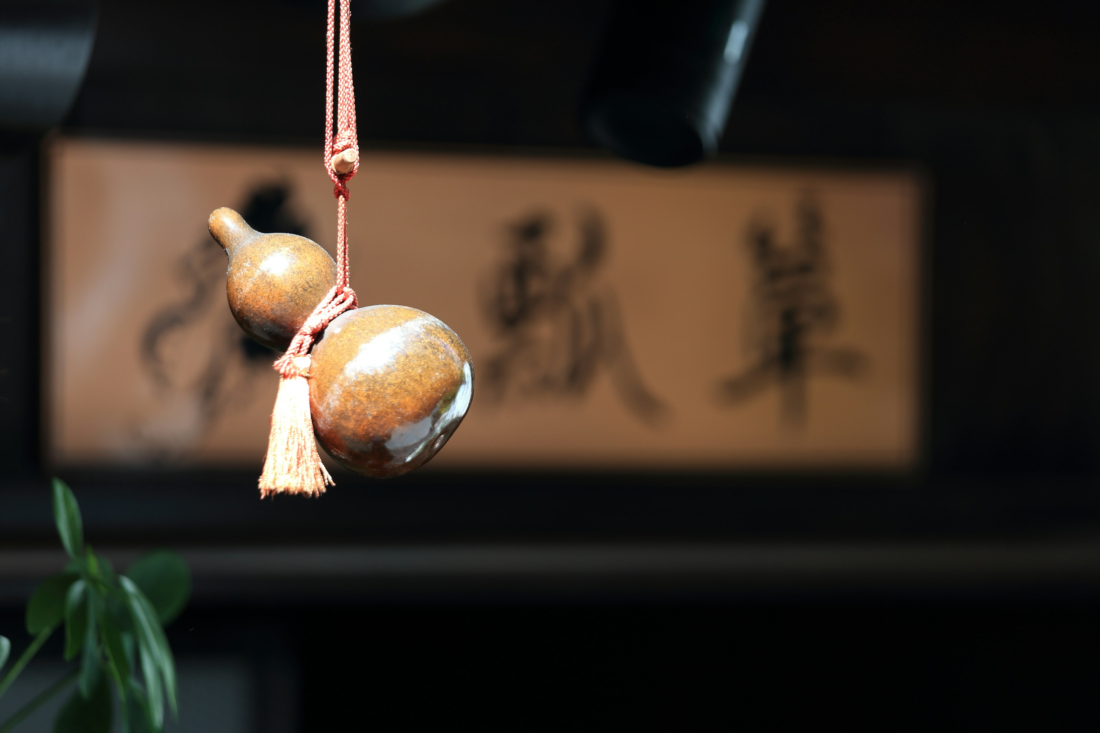 A wooden bell hanging with a tassel in front of a calligraphic sign