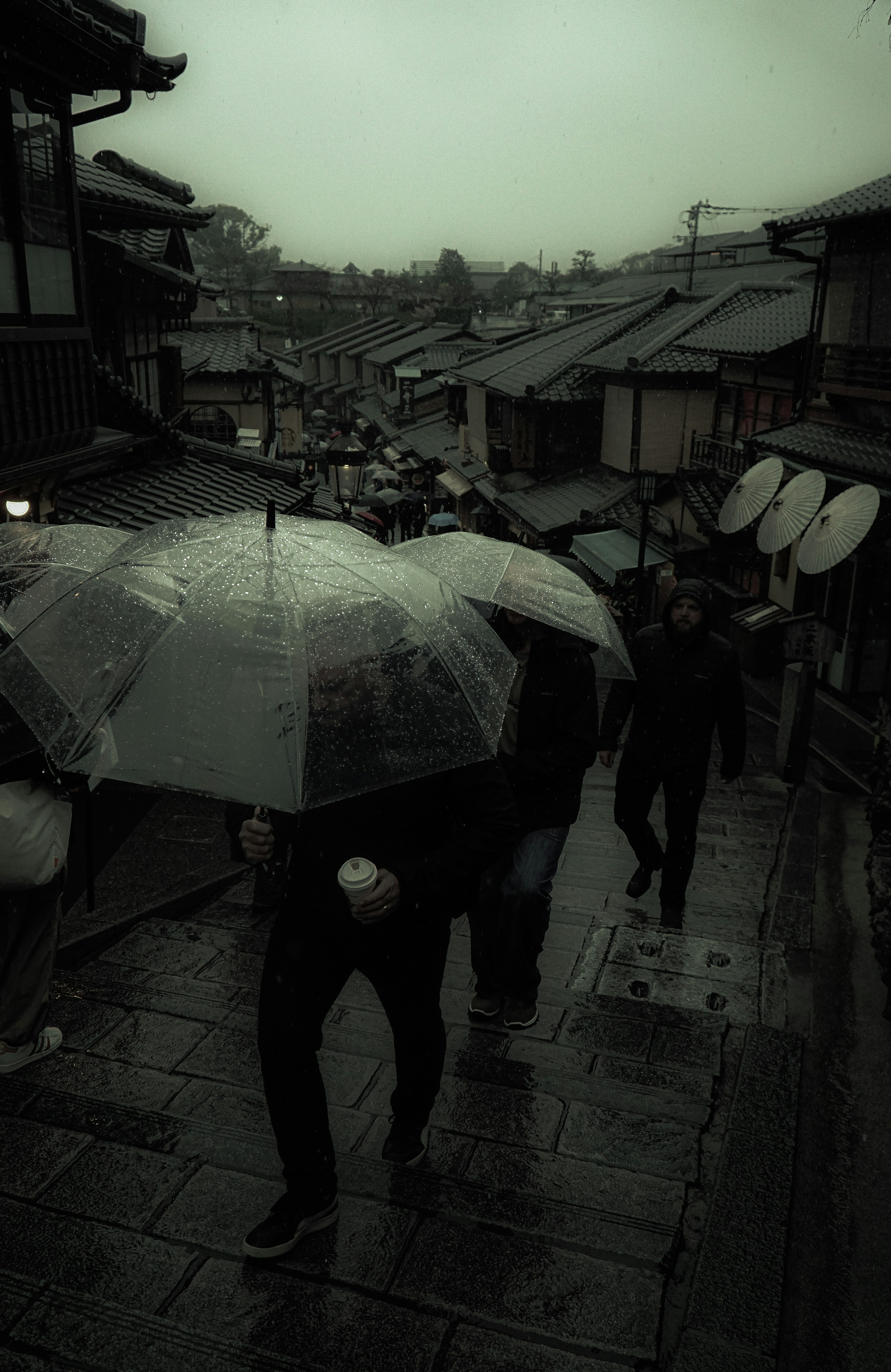 Menschen, die bei Regen mit Regenschirmen in einer historischen Straße gehen