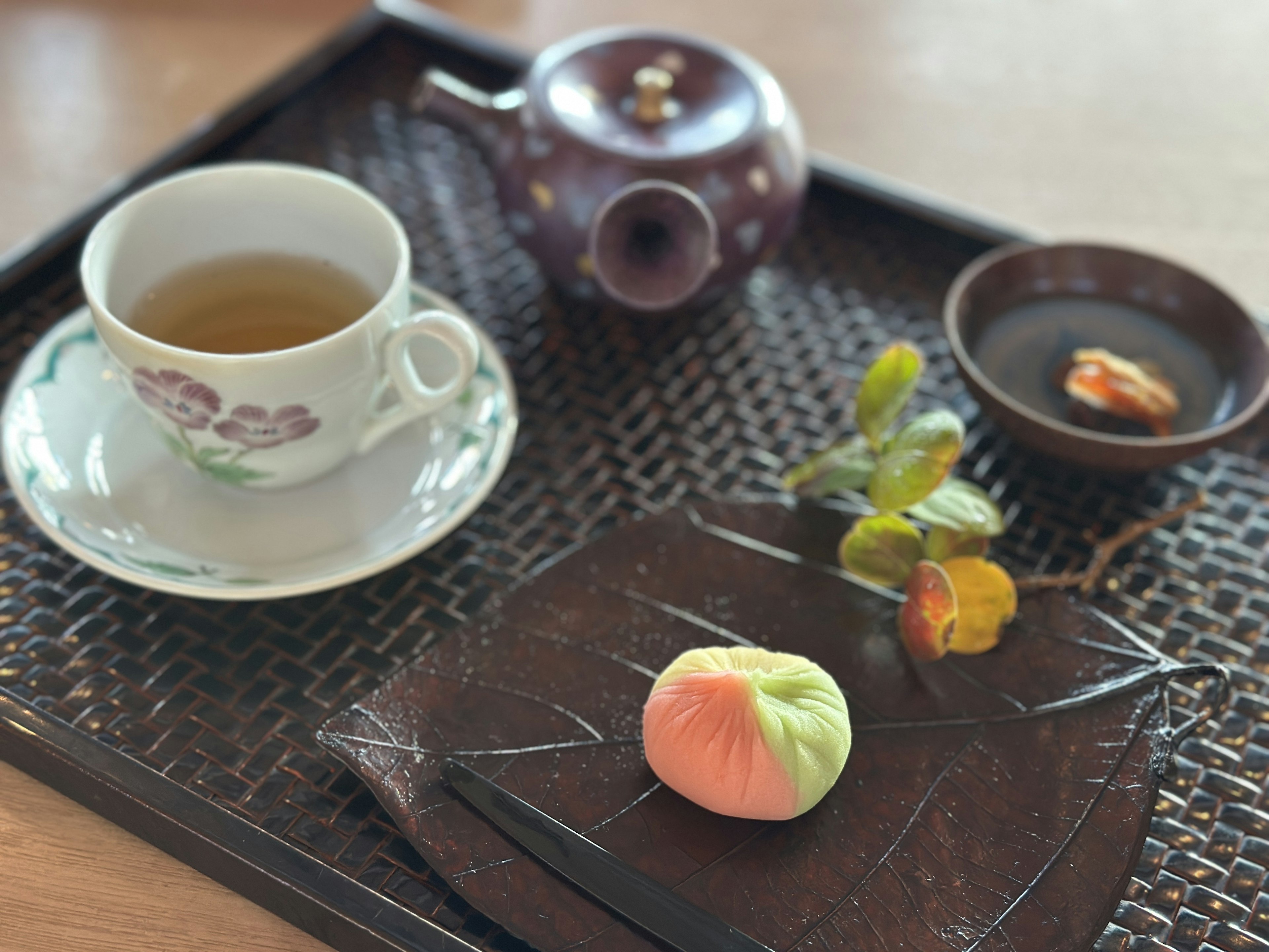 Taza de té y tetera con dulces japoneses en una bandeja