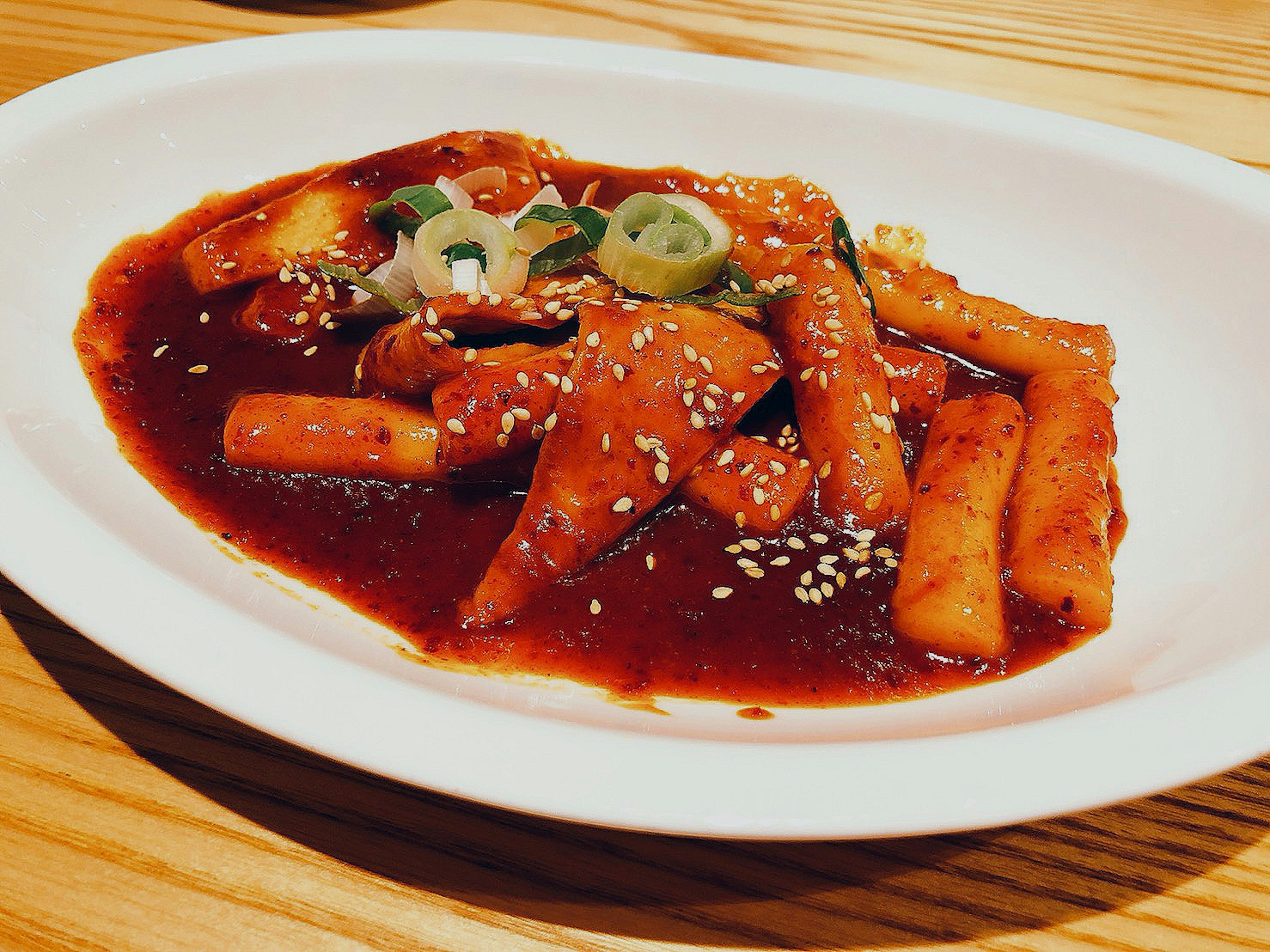 Plato de tteokbokki con salsa roja y cobertura de sésamo