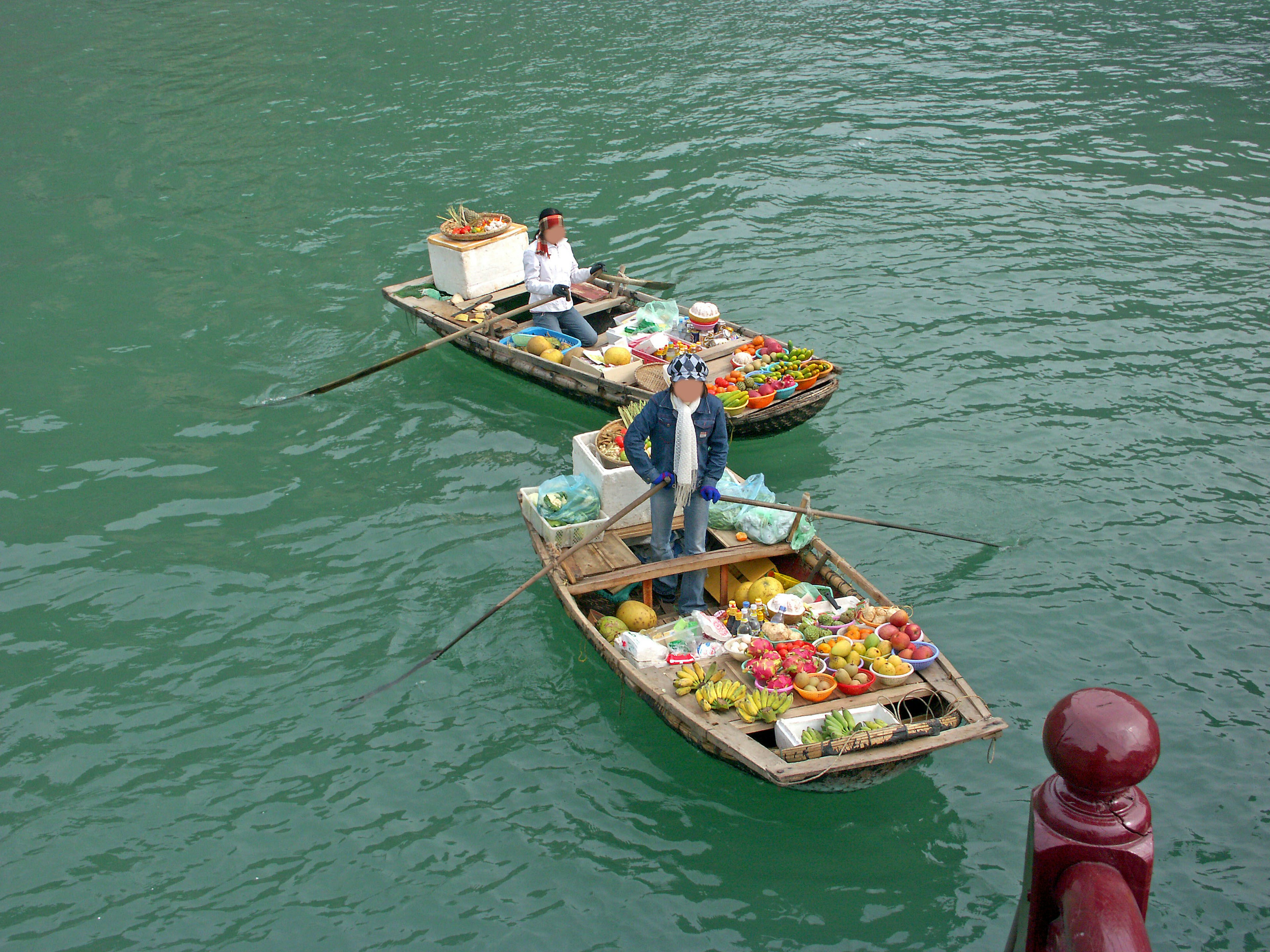 Dos pequeñas embarcaciones flotando en el agua vendiendo frutas