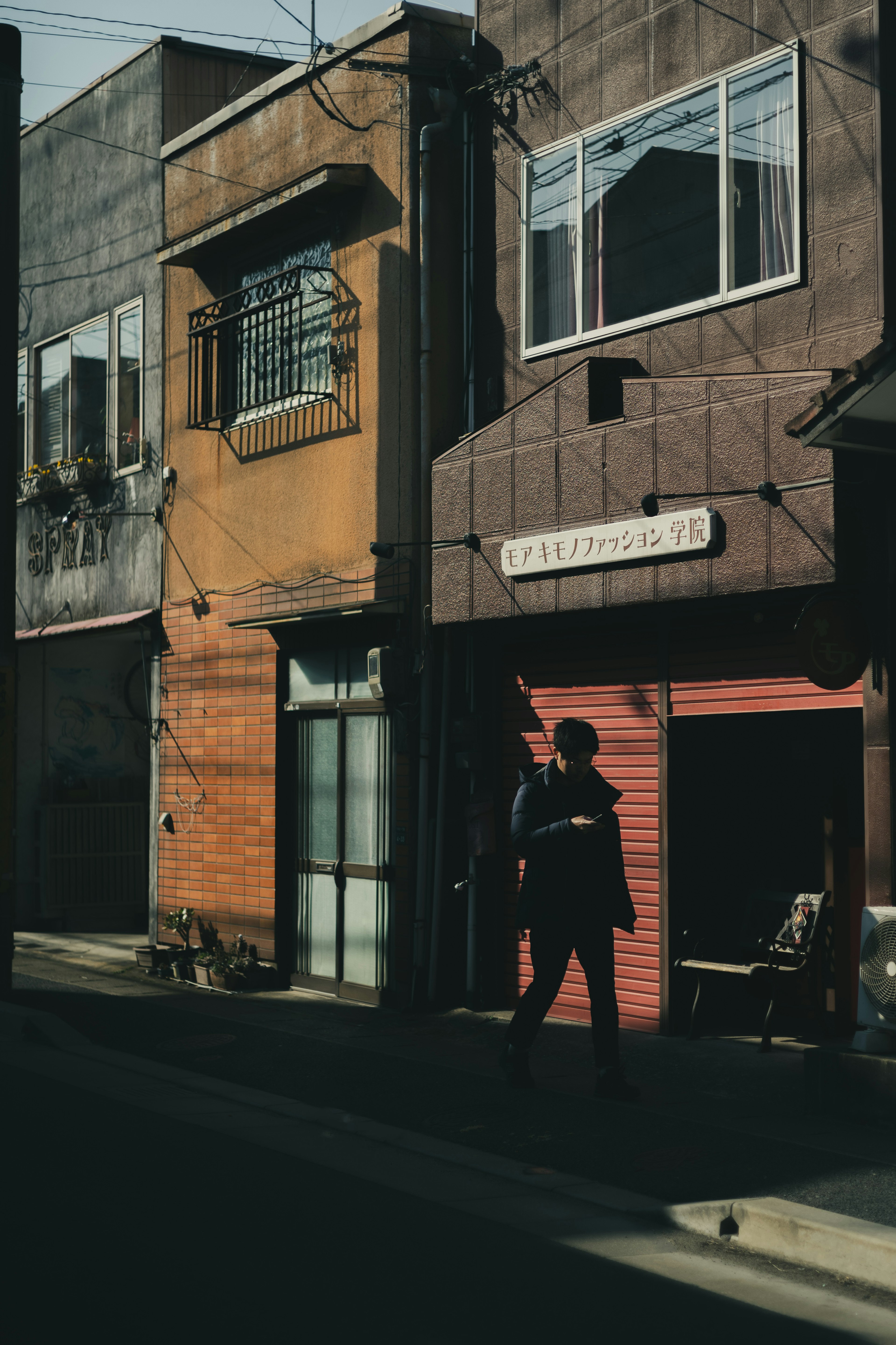 Silhouette of a person standing in a street scene with old buildings and a shuttered storefront