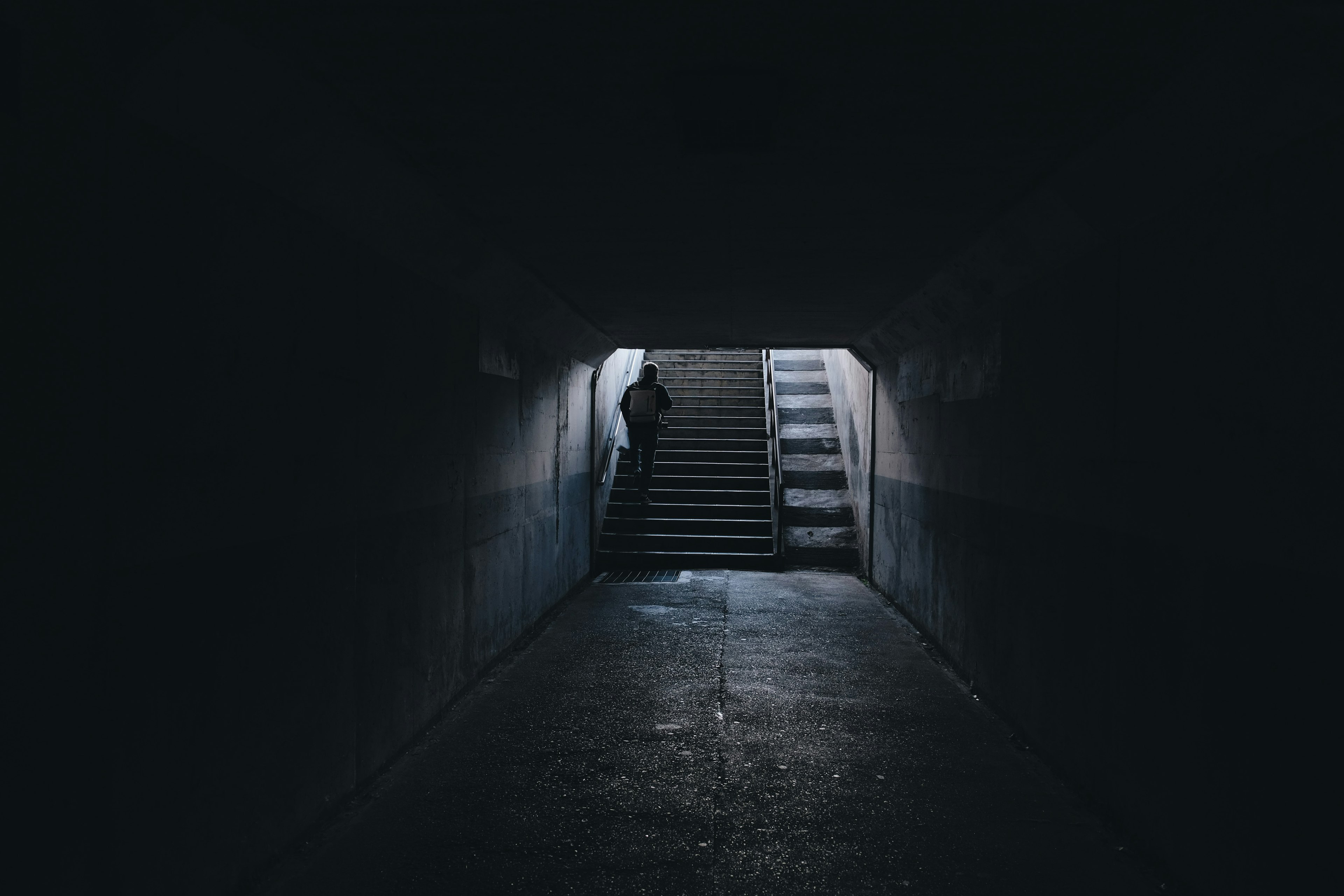 Eine dunkle Tunnelszene mit sichtbaren Treppen, die von schwachem Licht beleuchtet werden