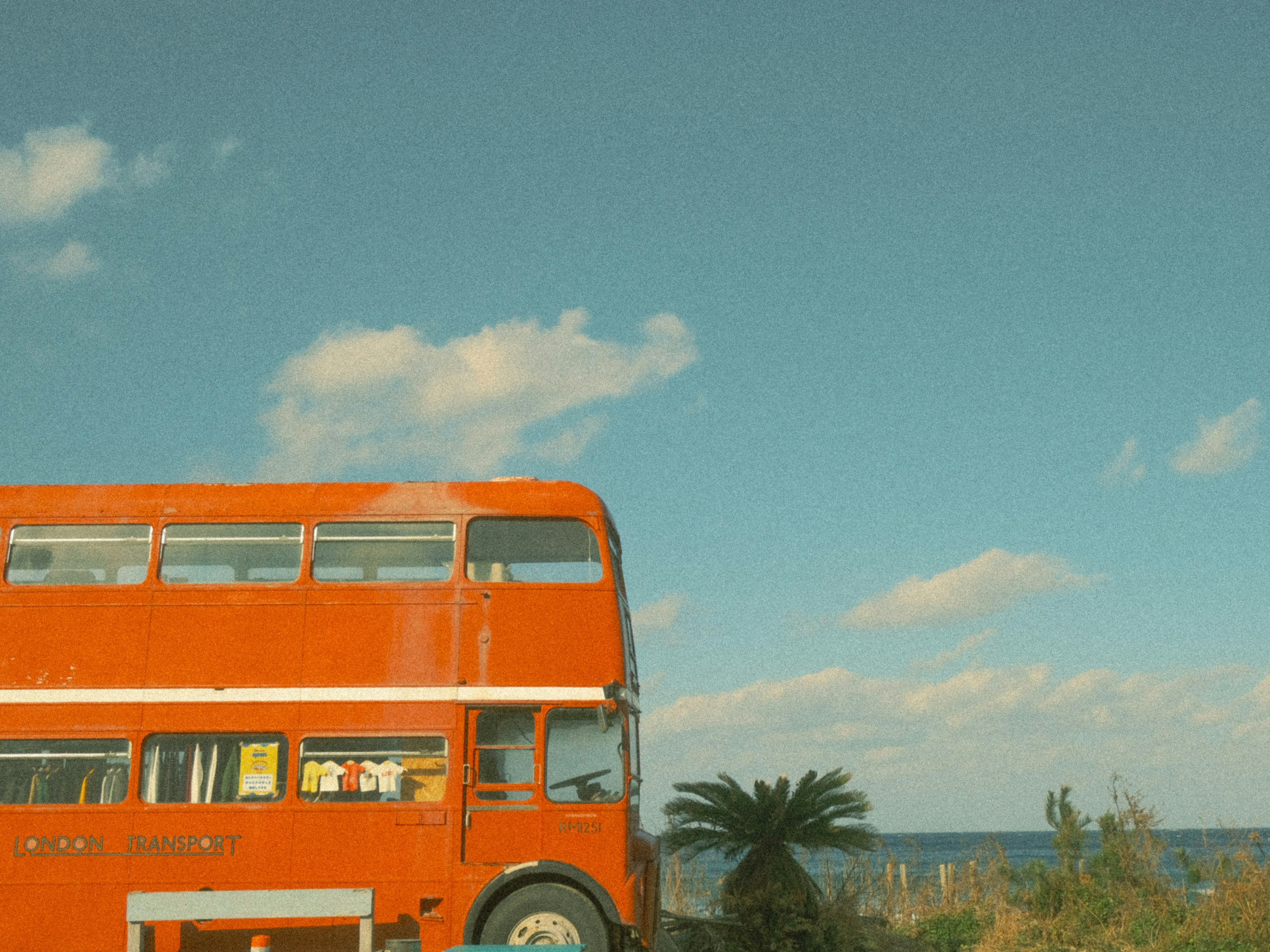 An orange double-decker bus parked near the sea