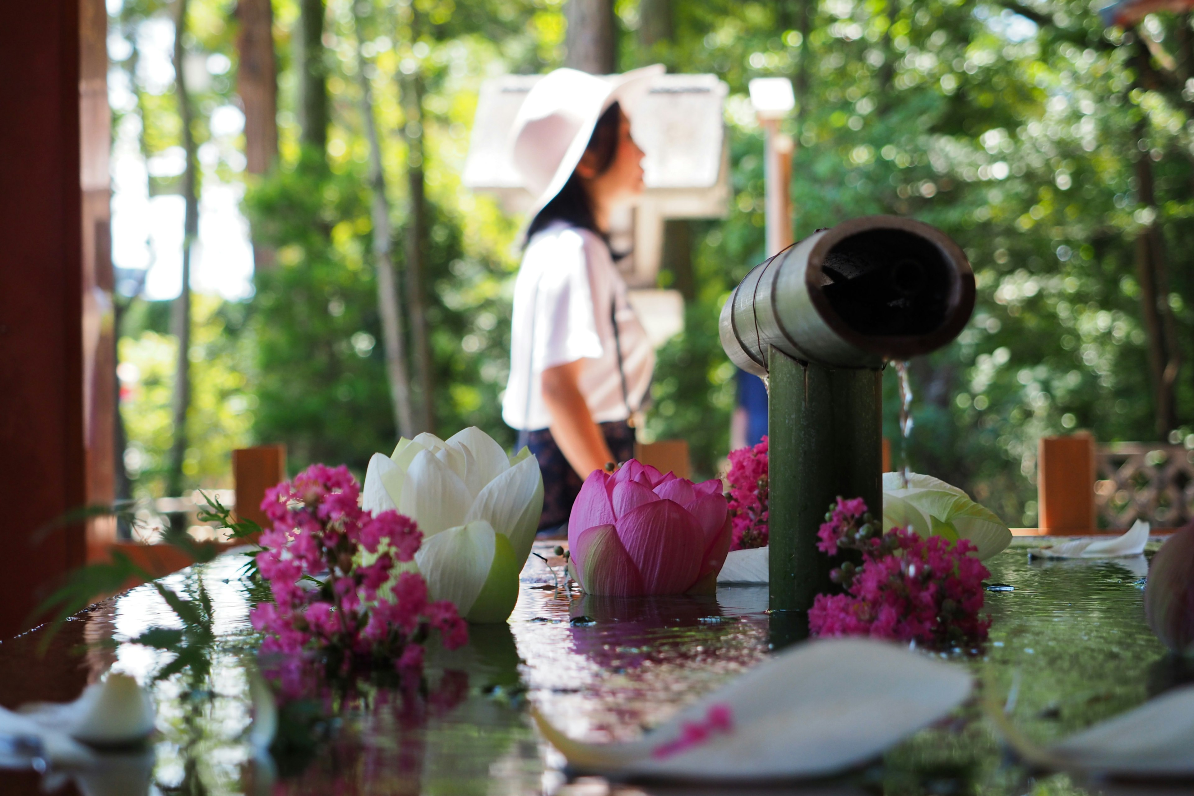 緑の背景の中で立つ女性の後ろ姿と花々の装飾