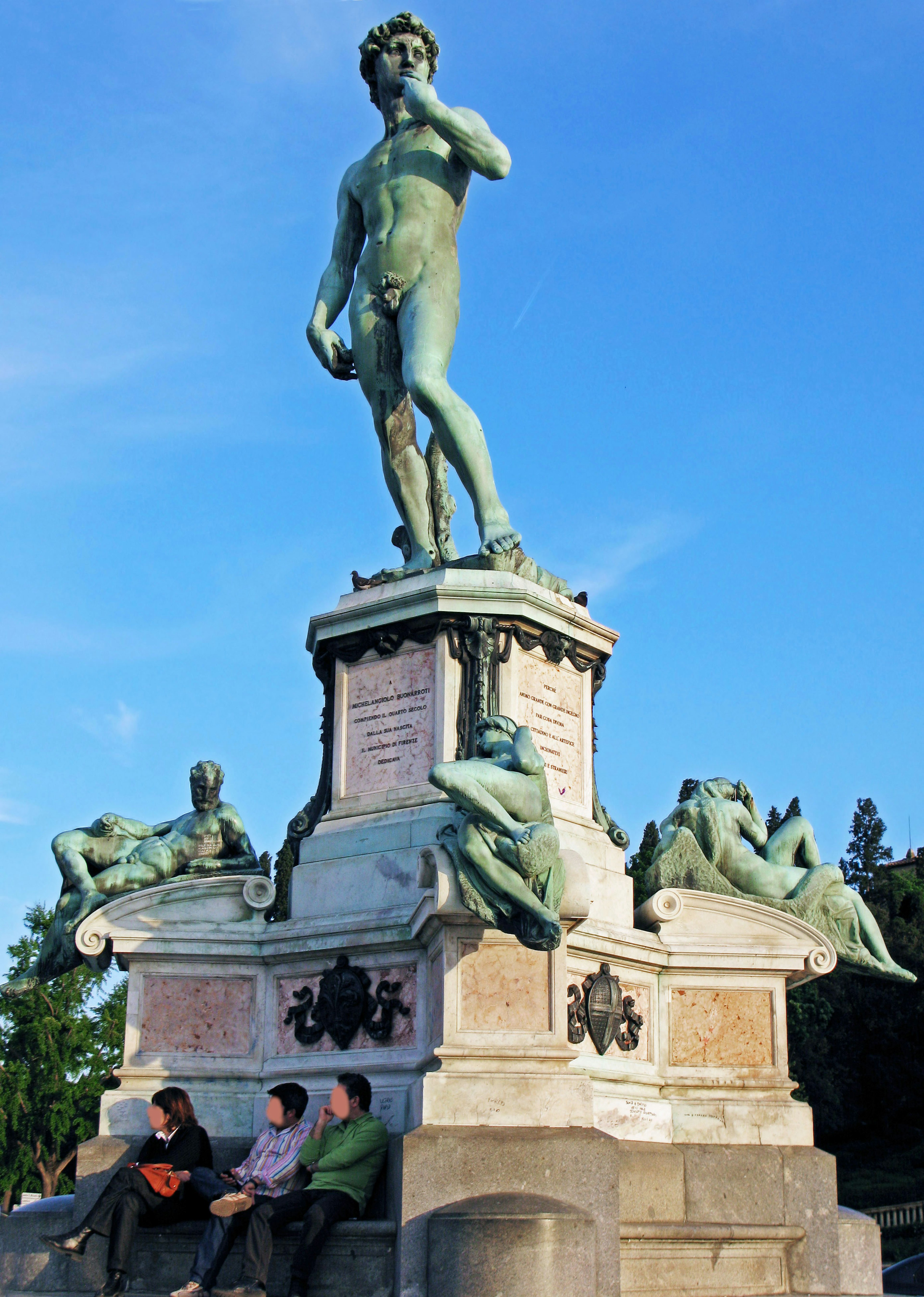 Statue of David under blue sky with surrounding sculptures