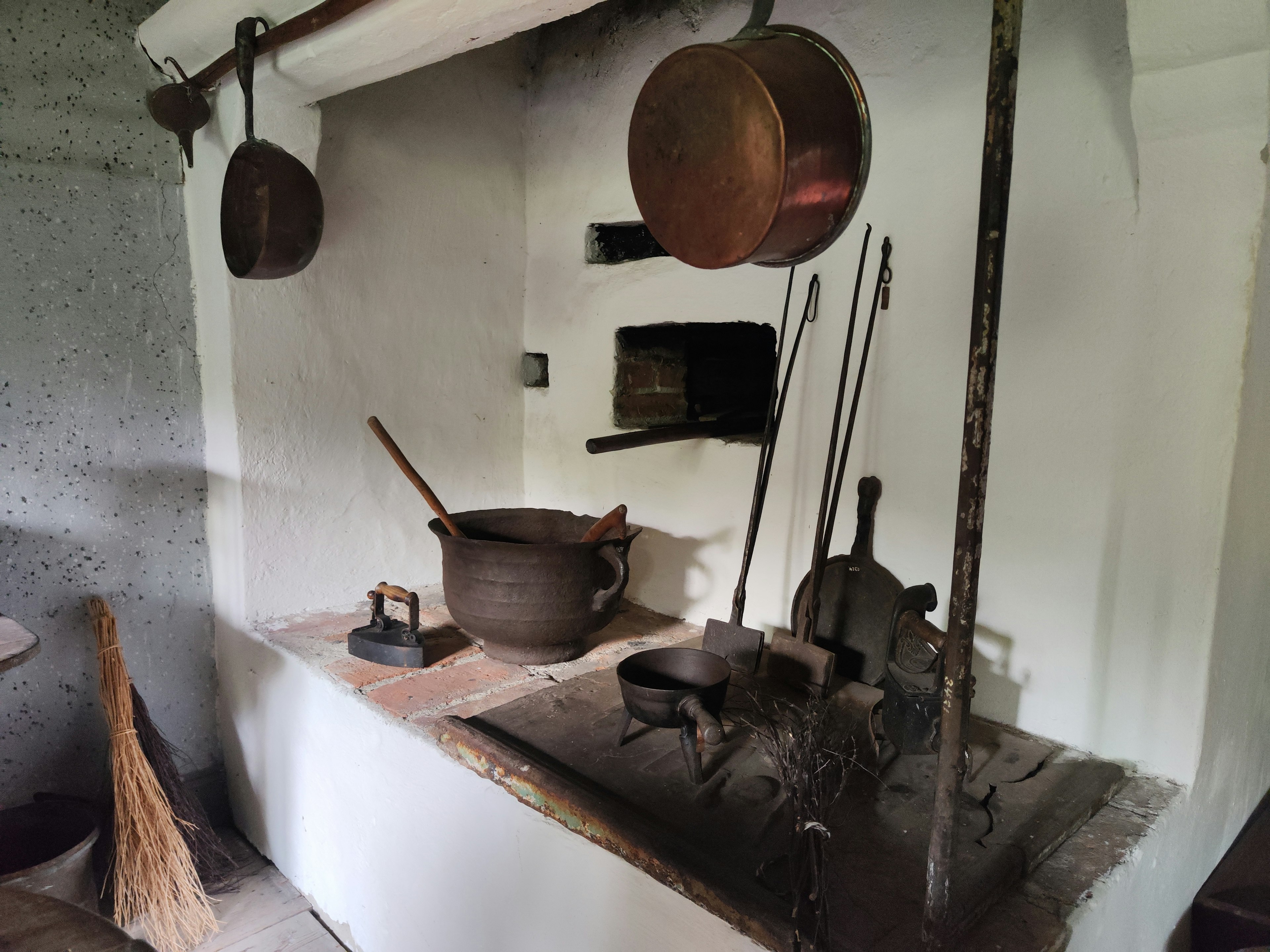 Área de cocina tradicional con una estufa antigua y ollas colgantes