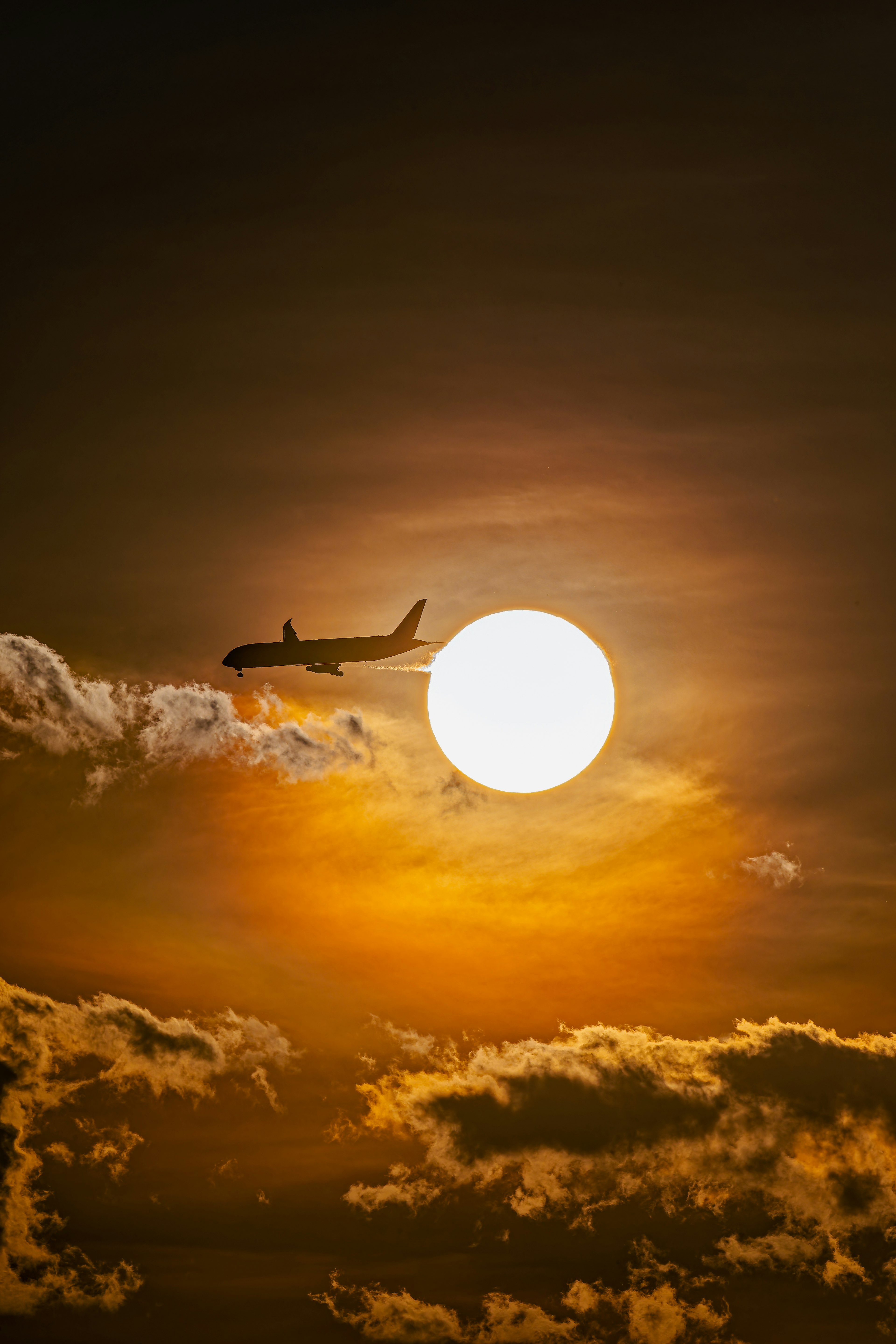 夕日を背景に飛行機が飛んでいるシルエット