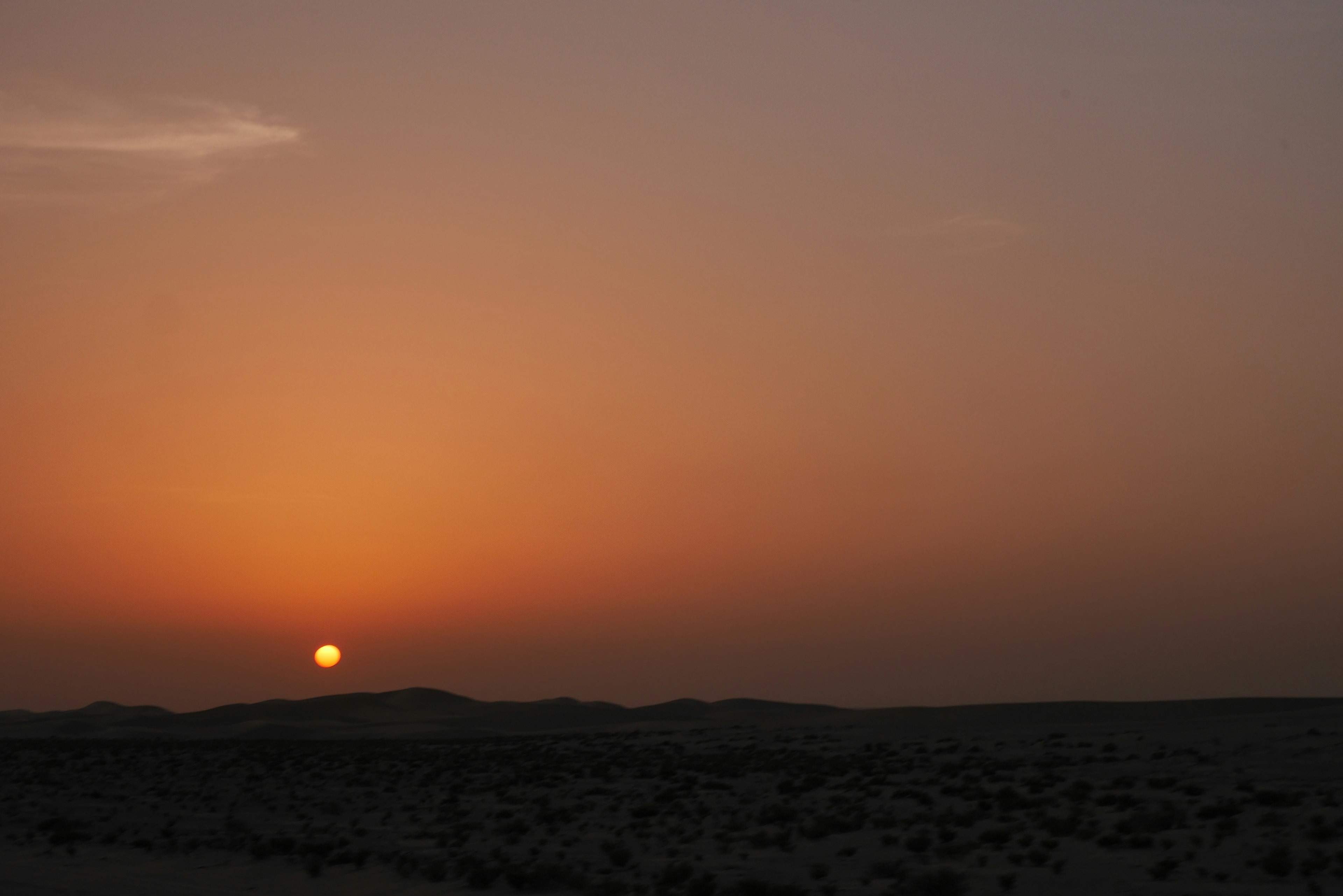 Paisaje desértico al atardecer con cielo naranja